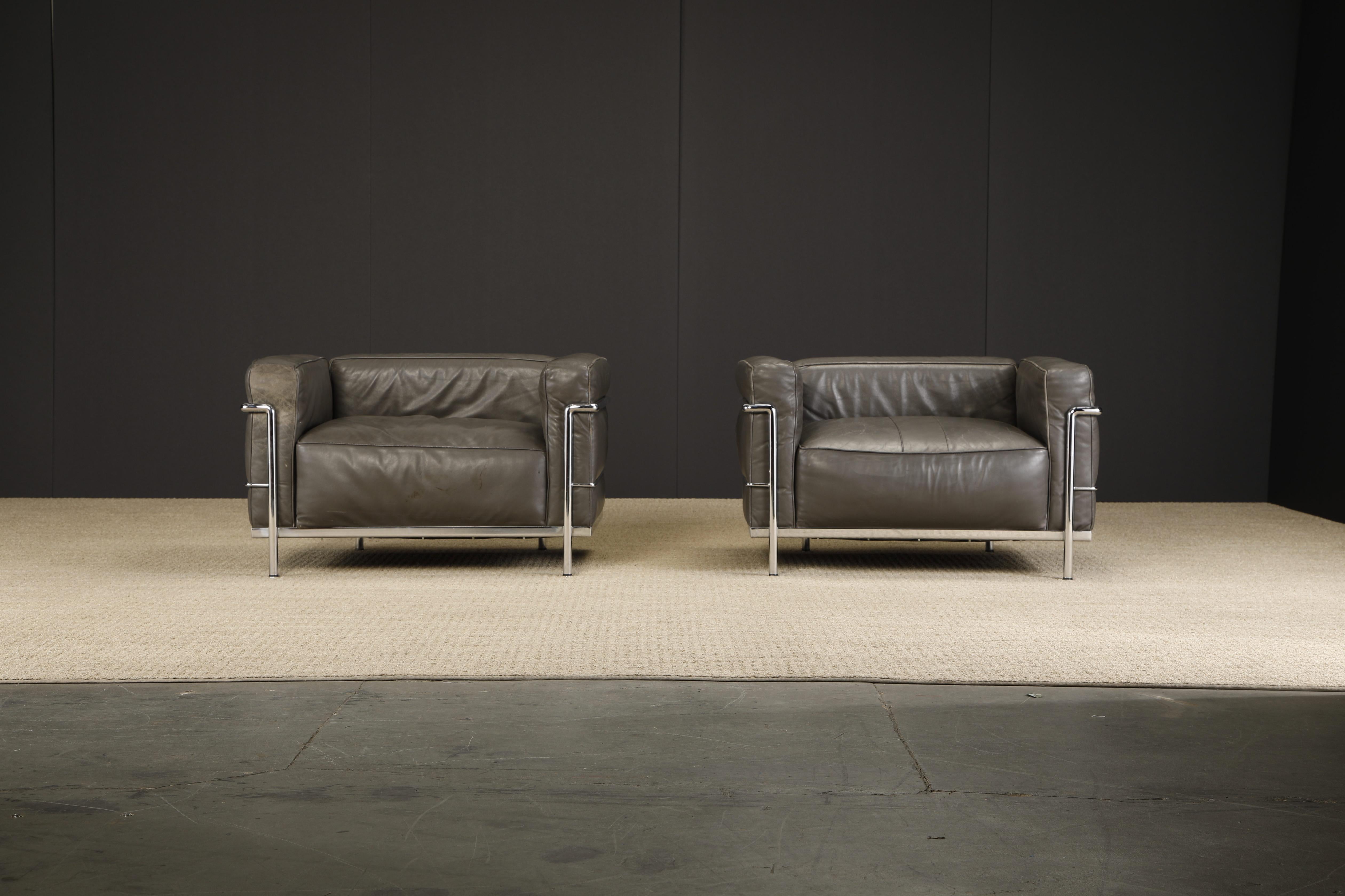 An incredible pair of early production year (ideal for collectors) 'LC3' club chairs in grey leather, by Le Corbusier, Pierre Jeanneret and Charlotte Perriand for Cassina, circa 1970s, both chairs are signed with Cassina model and early inventory