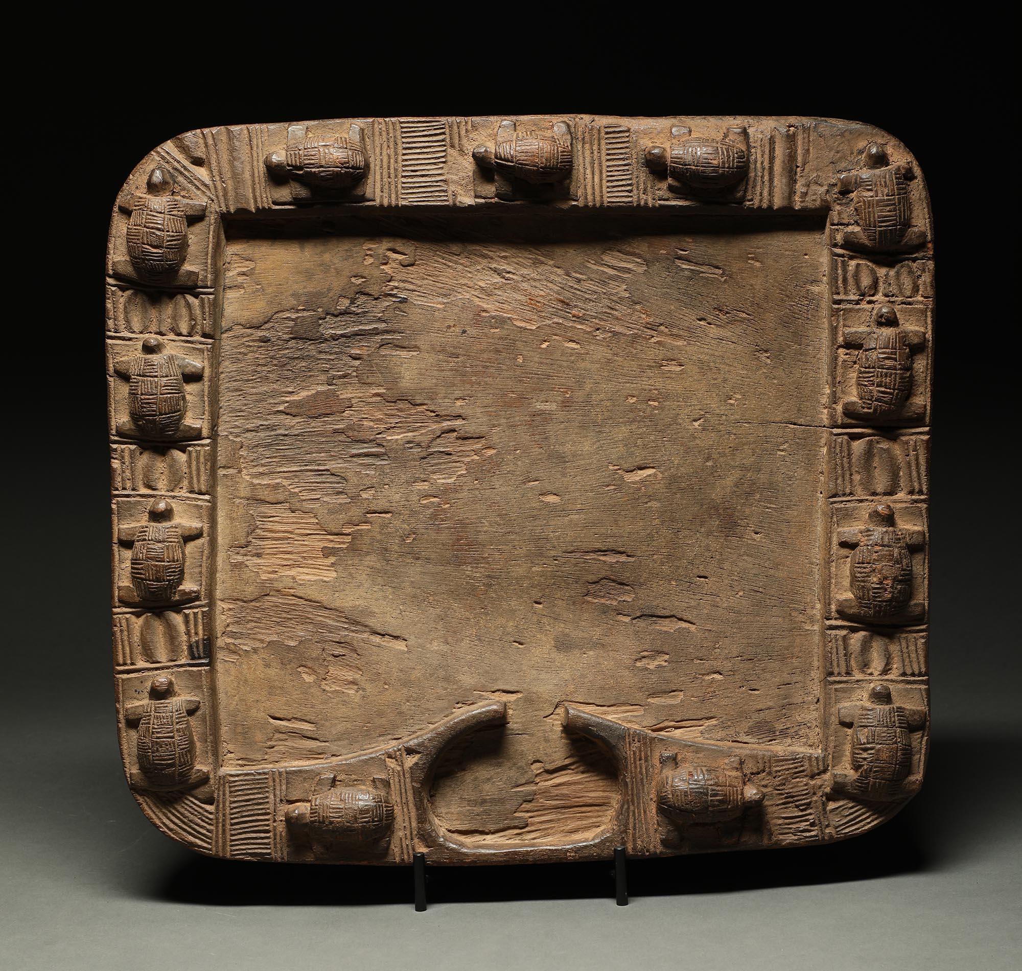Very early Yoruba divination board, a rare example with a row of turtles going around the edge of the board. Tilts slightly forward with two short legs on bottom. Carved receptacle on bottom to hold divination pieces. Very dense, heavy wood. Early