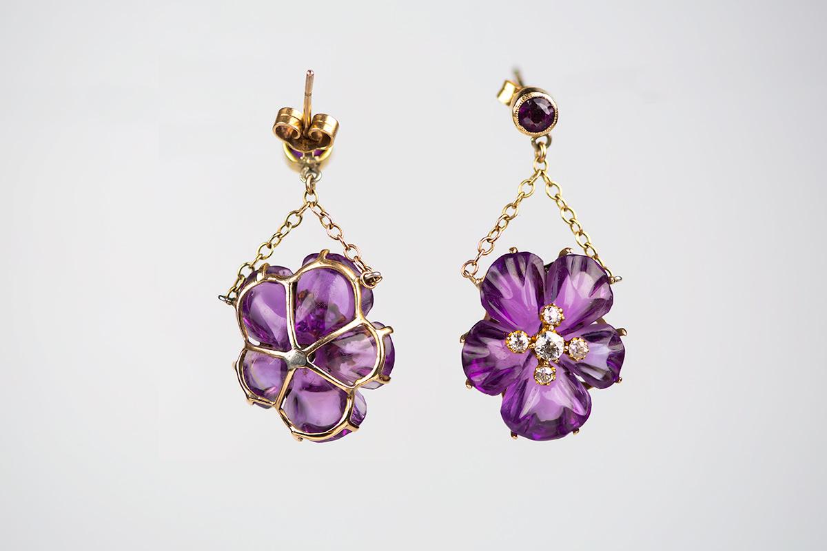 A finely carved pair of Amethyst earrings in the form of a Pansy with an old cut diamond cluster centre, hanging on gold chain with a single Amethyst top collet, and post  ear fittings. 
Measures 16 mm in width and 35 mm in drop.
Antique piece (over