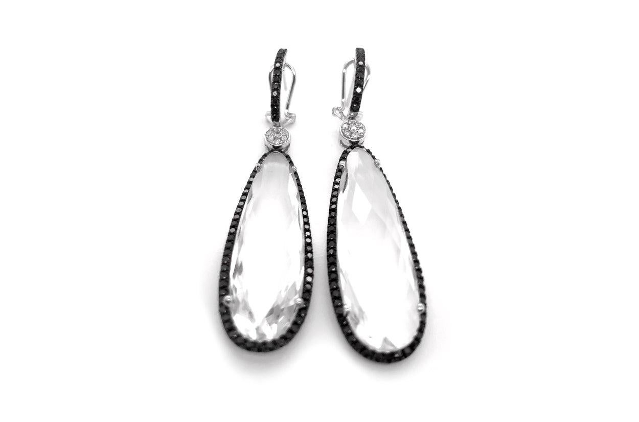 Radiate elegance with these stunning 18kt White Gold Drop Earrings. At their heart, clear quartz drops, as pure as crystal tears, dangle gracefully, their transparency evoking a sense of pristine beauty. Surrounding these drops are the striking