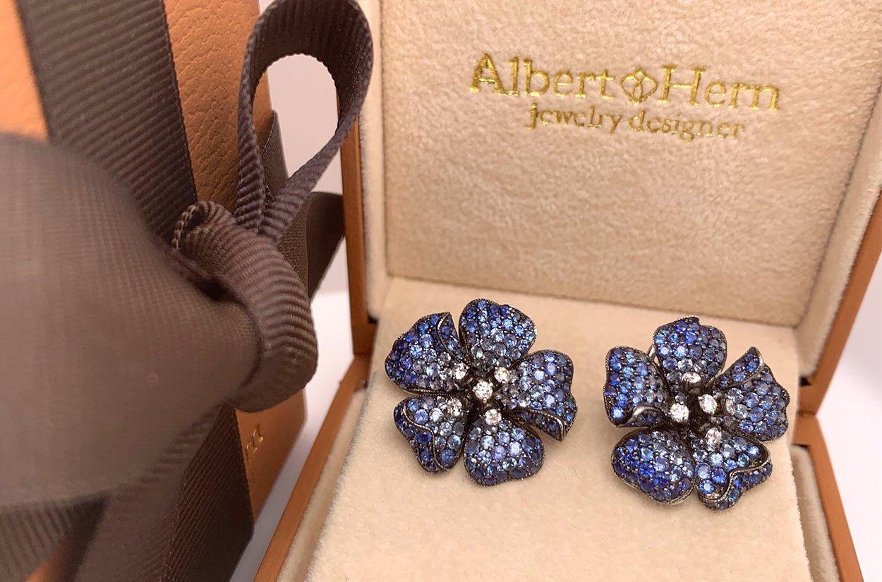 These exquisite earrings are a harmonious blend of nature's beauty and timeless elegance. Crafted in 18kt gold adorned with dazzling sapphires and diamonds, they evoke the delicate allure of blooming flowers. The lustrous black rhodium detailing
