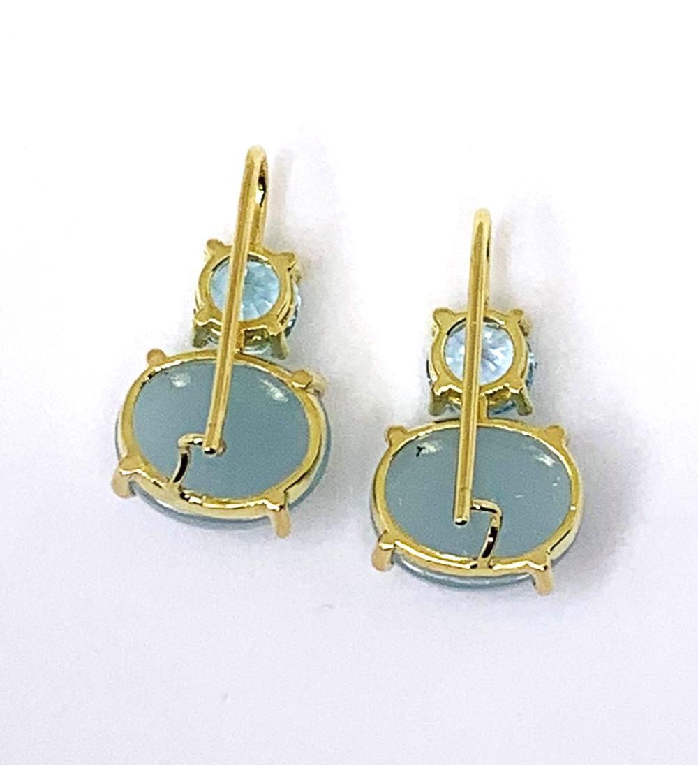 Powder blue aquamarines in two different forms are featured in these stylish, 18k yellow gold drop earrings. Two transparent, faceted aquamarines set atop two translucent cabochon aquamarines. These aquamarines weigh a total of 10.85 carats. The