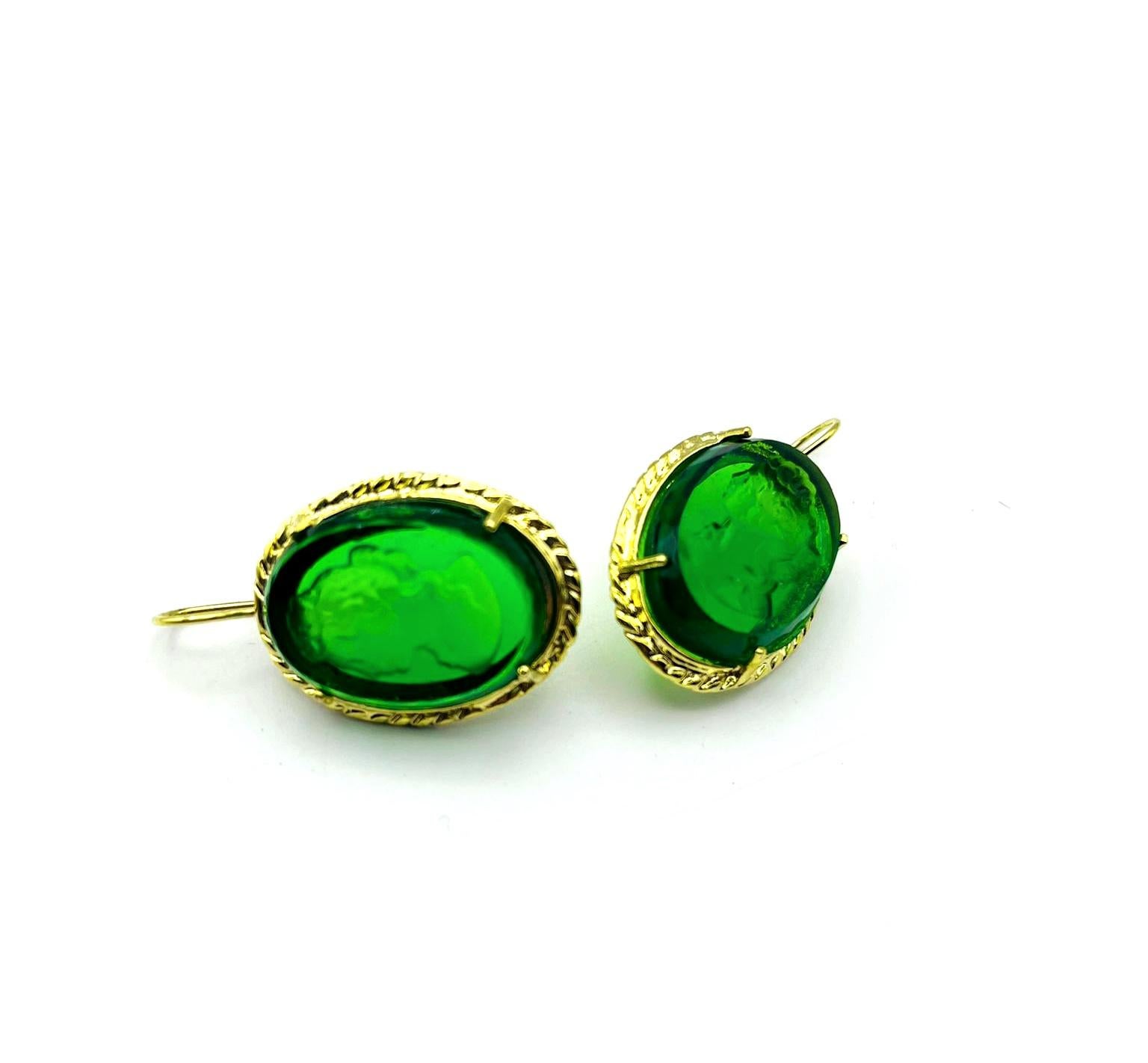 Earrings by Patrizia Daliana in 24 KT gilded bronze with hand-carved and ground emerald green Murano glass depicting an ancient Roman woman's head and glass crystals. To wear it to the ear, a suitably shaped bronze wire is used. To fix the stones to