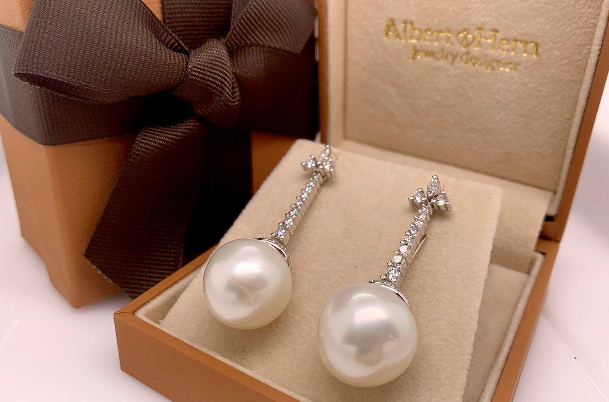 These enchanting dangle earrings are a symphony of grace and opulence. Cascading from lavish arrangement of diamonds, they culminate in two lustrous South Sea pearls, each a radiant treasure from the depths of the ocean. With every sway, these