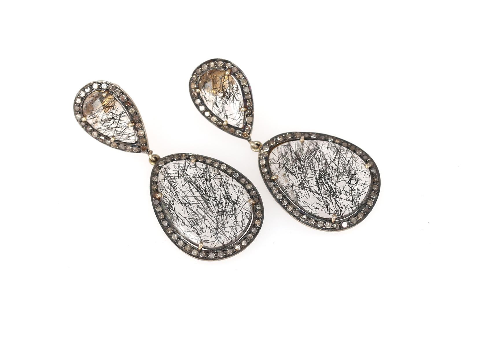 Hairy stone Earrings in Gold Silver and with Rose-cut Diamonds.

Very unusual, almost transparent stone with natural inclusions creating a superb 3D effect. Rose-cut Diamonds are mounted in a pear shaped form around the stone. The earrings sit