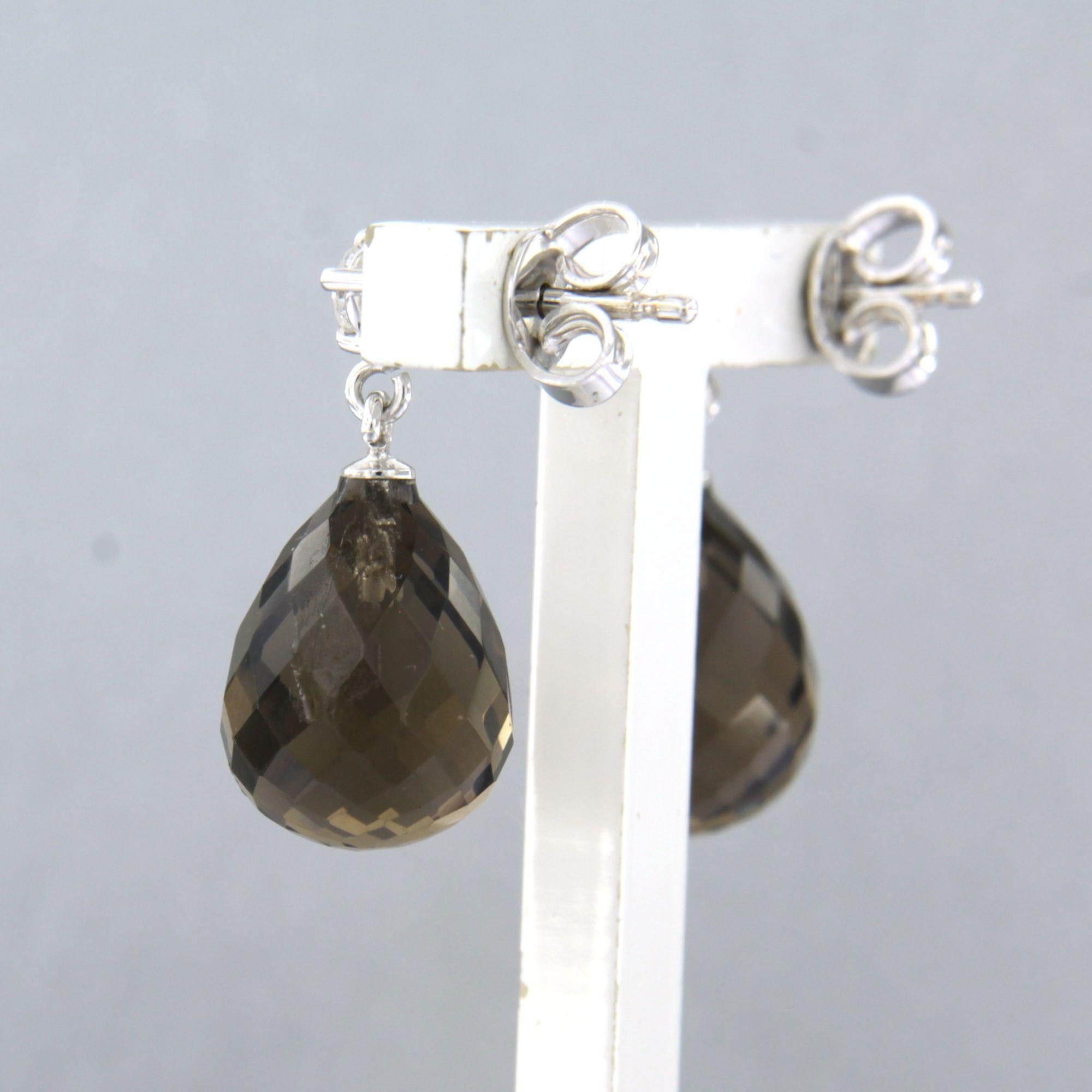 Boucles d'oreilles en or blanc 18k serties de quartz fumé et de diamants taille brillant jusqu'à 0,20 ct - F/G - VS/SI

Description détaillée :

Les boucles d'oreilles mesurent 2,1 cm de long et 9,8 mm de large.

Poids total : 4,6 grammes

Set avec