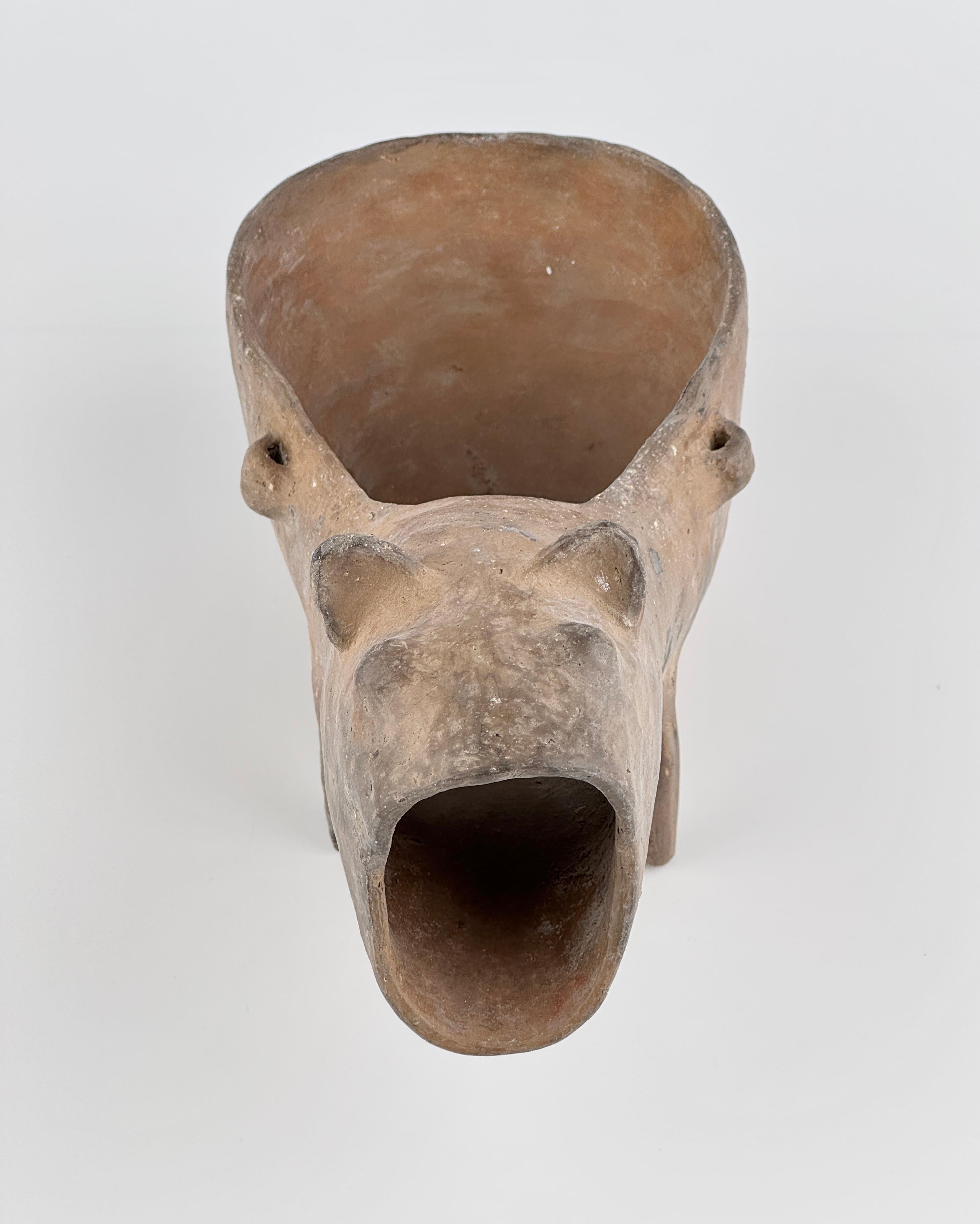 This terracotta vessel was fired to a warm yellow-brown that shows subtle oxidation marks across the surface. Entirely unglazed, it retains a matte, tactile finish with fine pores and minor rim abrasion—evidence of natural ageing—yet the body
