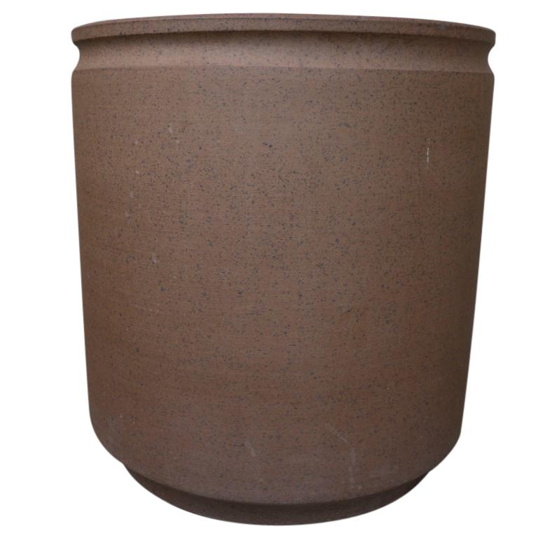 A smooth cylinder shape with incised top lip detail and a textured brown clay color as is commonly seen in Earthgender pottery by David Cressey.