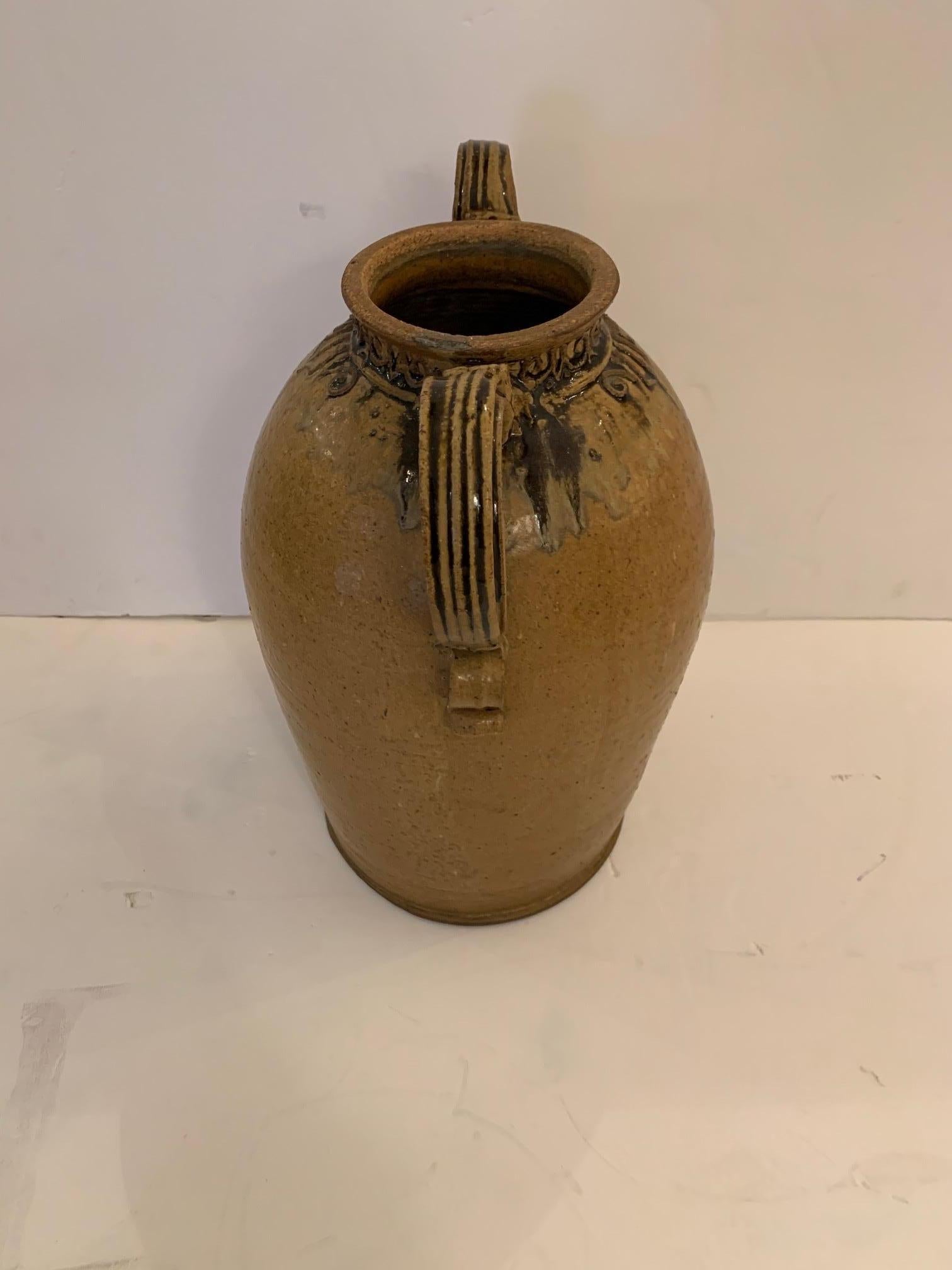 Artisan made beautiful earthy pottery vessel in a gorgeous warm terracotta color with great curlicue design around the top with two stylized handles. Signed on bottom.