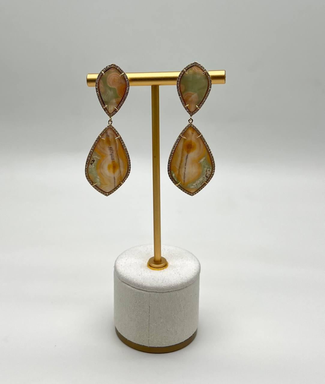 A pair of unique drop earrings featuring natural quartz set in a gold frame. The left earring showcases a teardrop-shaped quartz with earthy tones, bordered by a delicate gold trim. The top stone is a smaller, matching shape. Halo of Diamonds