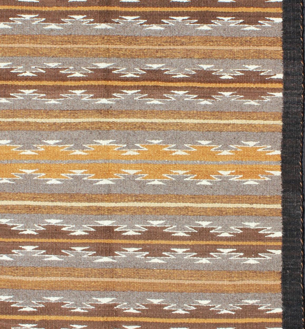 Dieser faszinierende antike Navajo-Kilim (ca. 1940) wurde in der ersten Hälfte des 20. Jahrhunderts in den Vereinigten Staaten gewebt. Die aufregende und einzigartige Komposition besticht durch eine geometrische Komposition mit einem kreuzförmigen