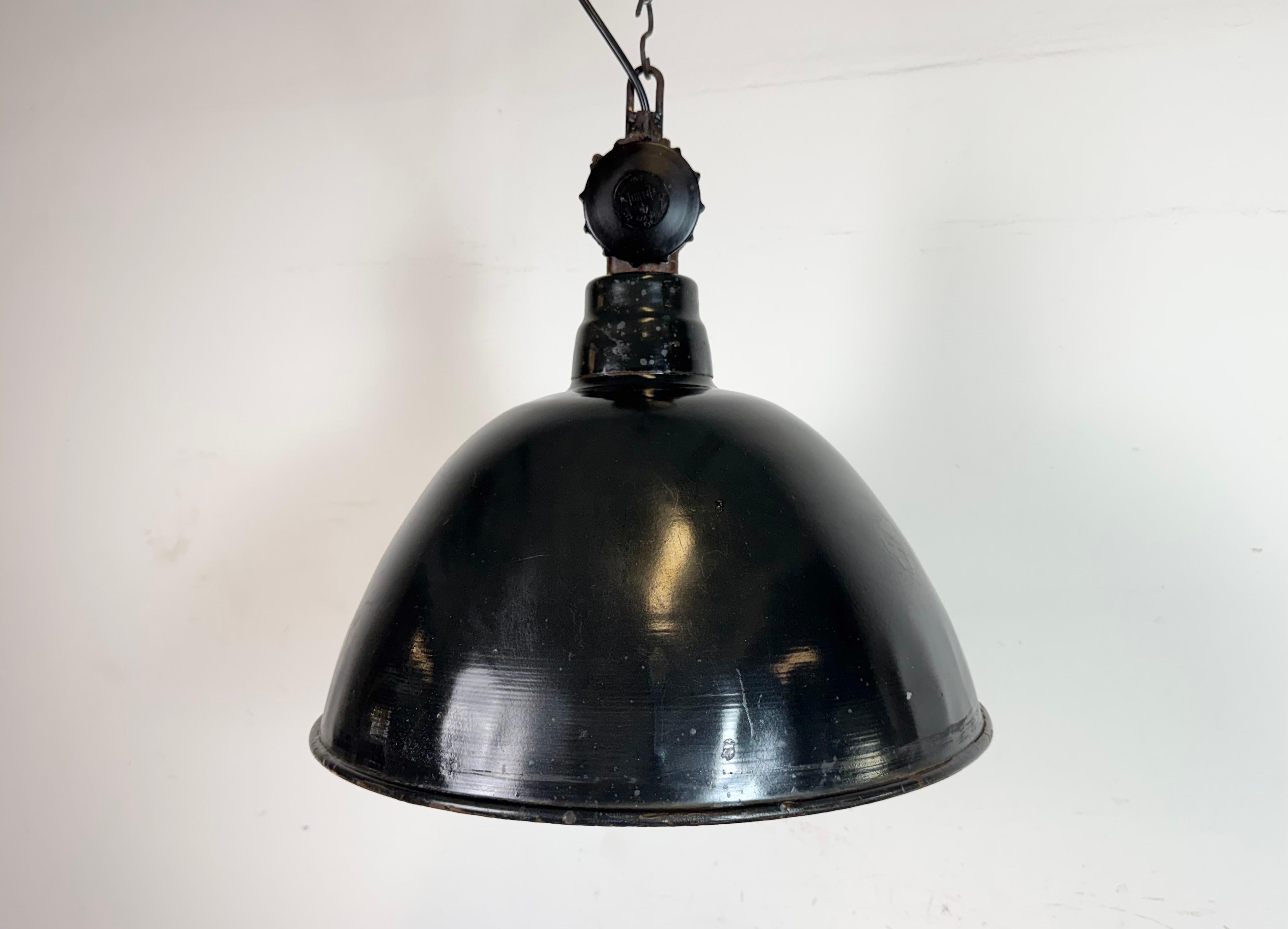 Lámpara de fábrica de esmalte industrial fabricada por LBD Veb Leuchtenbau Dresden en Alemania Oriental durante la década de 1950.Presenta pantalla de esmalte negro con interior de esmalte blanco y parte superior de baquelita.El casquillo de