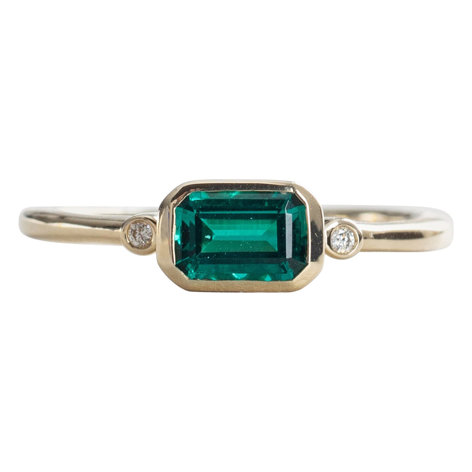 East west emerald stone bezel with diamonds set on 14k yellow gold.
Stone Shape: Emerald
Stone Type: Lab-created emerald
Metal Type: 14 Karat Yellow Gold
Stone size: 4mm x 6mm
Band width: 1.7mm
Diamond Clarity: VS
Diamond Color: G-H

Size 7 is ready