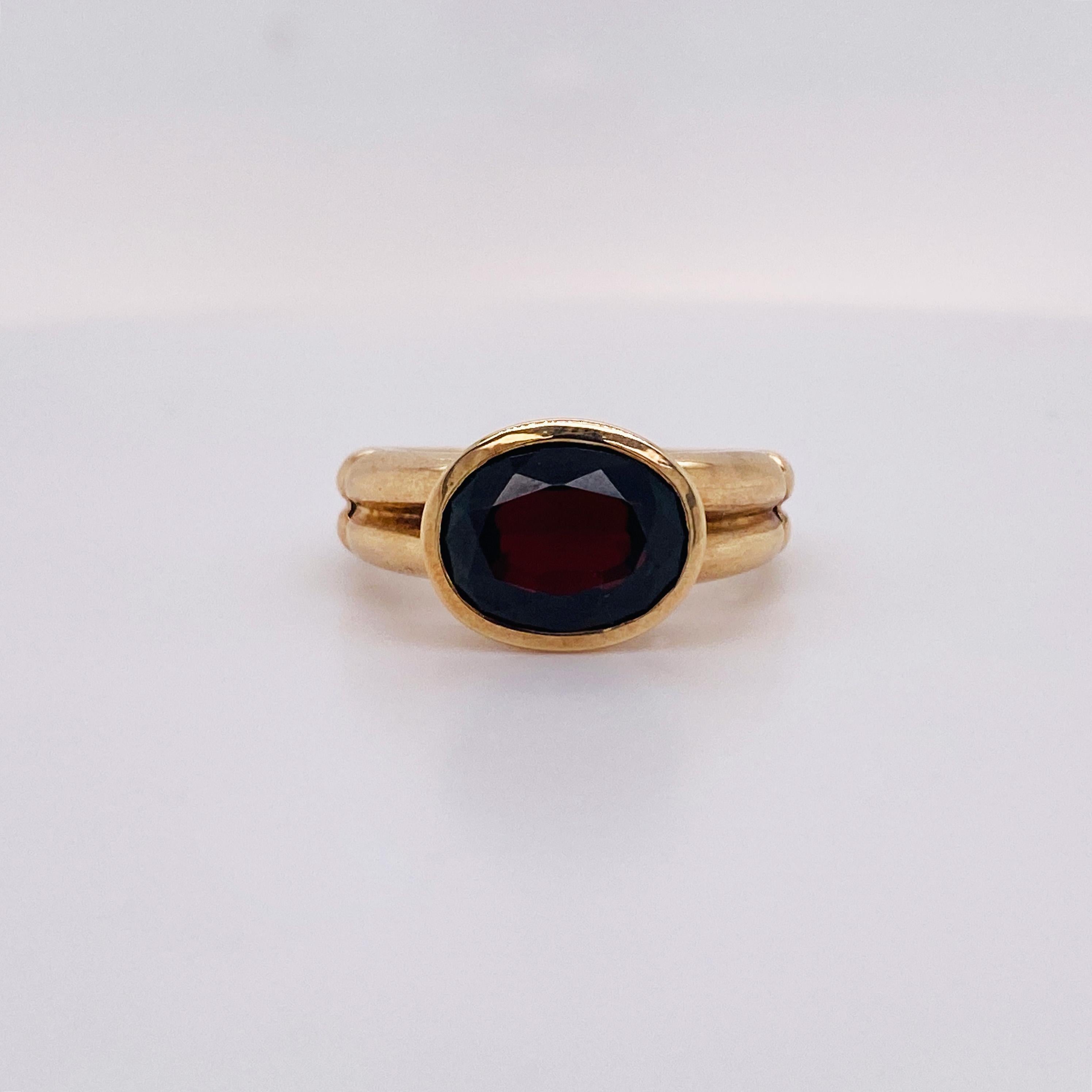 This modern bezel-set garnet is 3.10 carat oval shape and has a fabulous, structured design. The ring is solid 14 karat gold with a unique ribbed band This ring looks lovely on anyone’s hand as the band tapers and wears very comfortably! This
