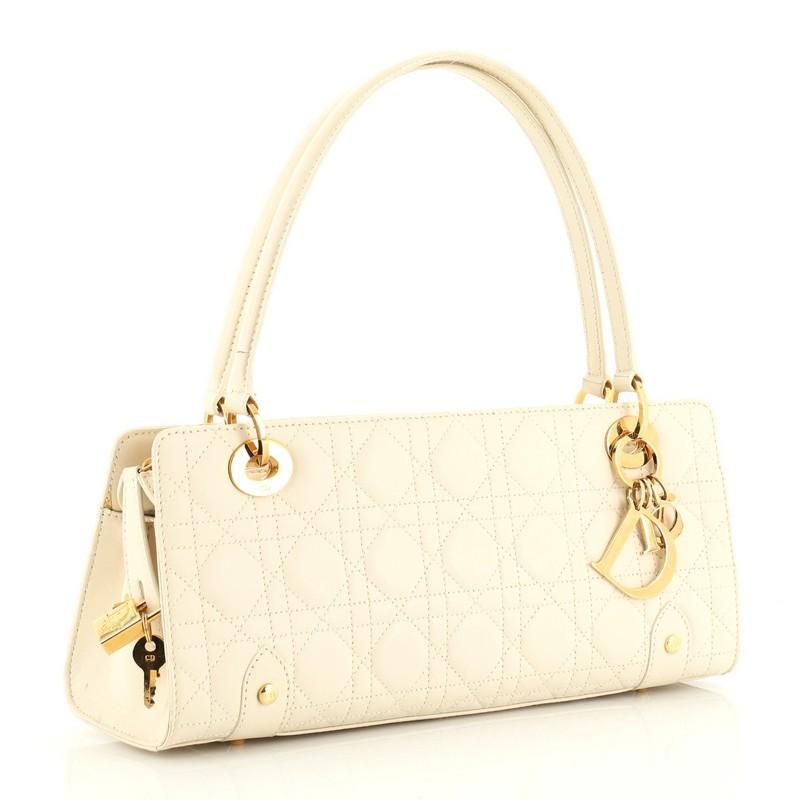 This Christian Dior East West Lady Dior Bag Stitched Cannage Leather Small, crafted from neutral stitched cannage leather, features dual flat leather handles with links, protective base studs, and gold-tone hardware. It's zip closure opens to a gold