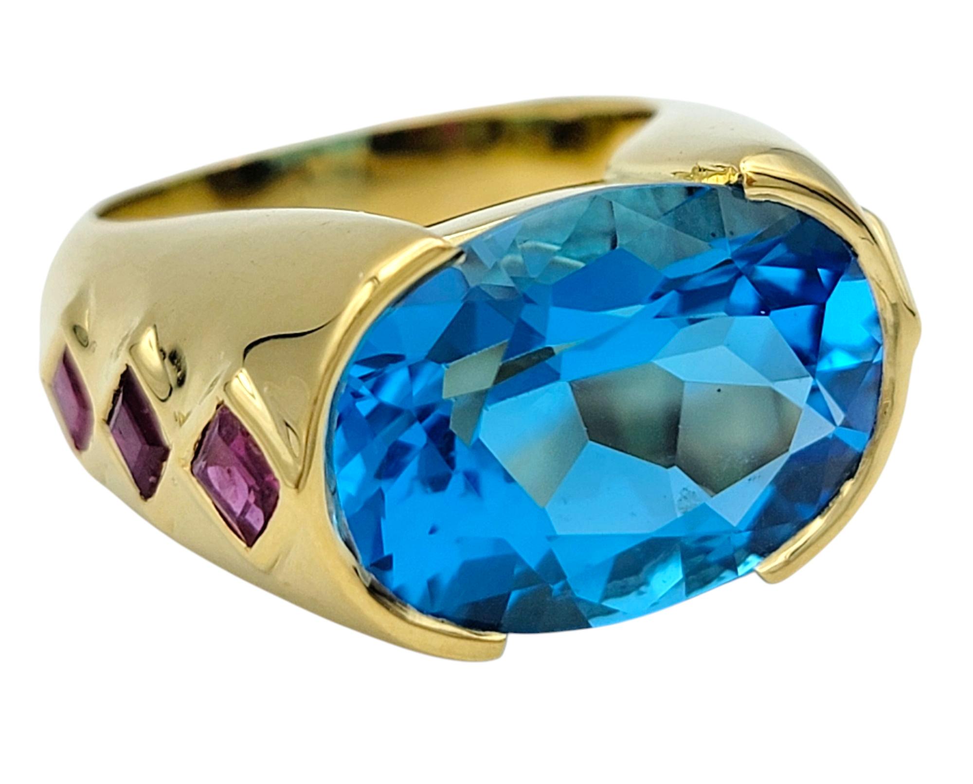 Contemporary East West Oval Cut Blue Topaz Cocktail Ring with Rubies in 18 Karat Yellow Gold For Sale