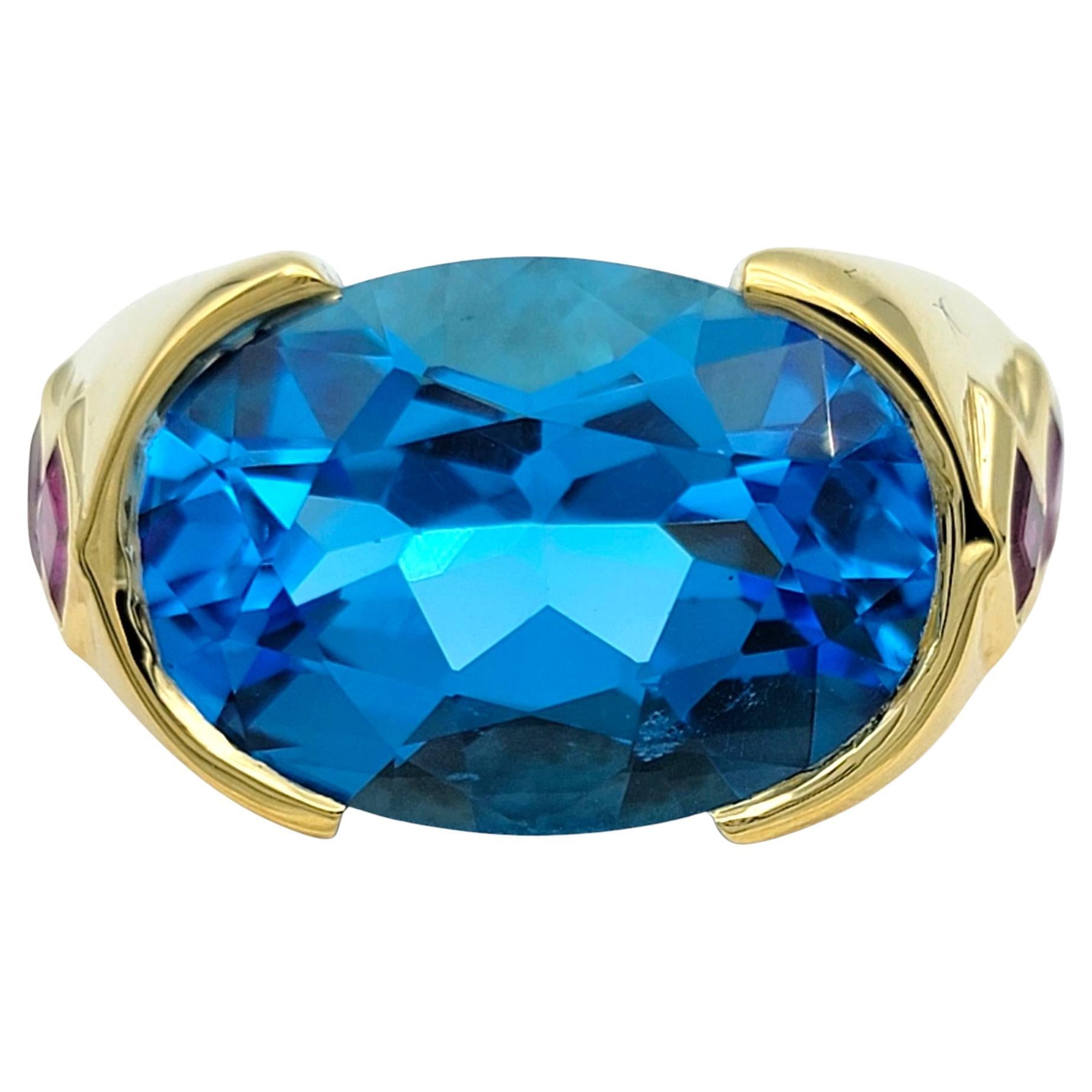 East West Anillo de Cóctel de Topacio Azul de Corte Oval con Rubíes en Oro Amarillo de 18 Kilates