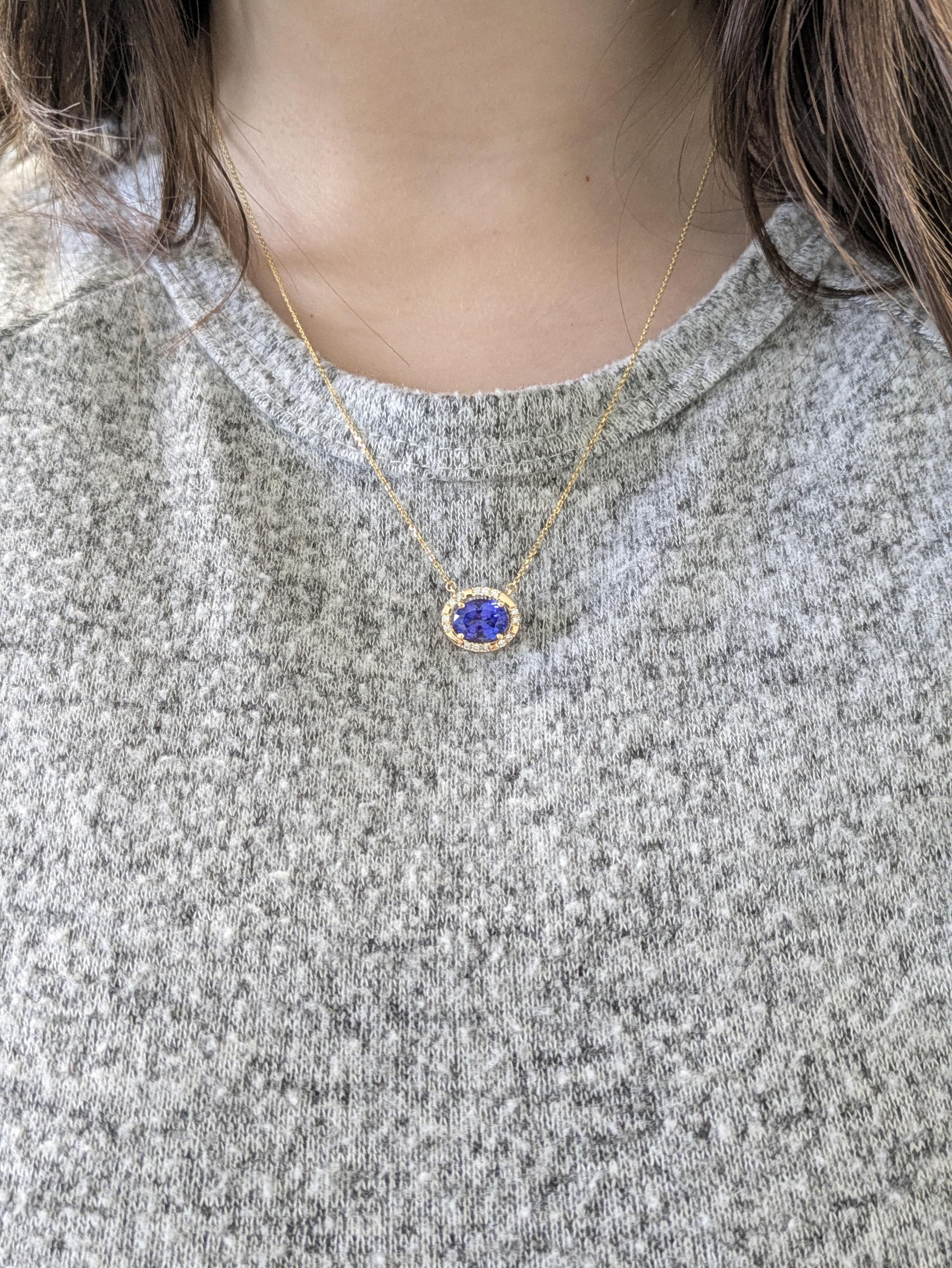 A chic oval tanzanite pendant set east-west in 14k solid yellow gold, surrounded by a sparkling halo of natural diamonds. With its attached chain, this modern yet elegant piece effortlessly blends contemporary style with timeless
