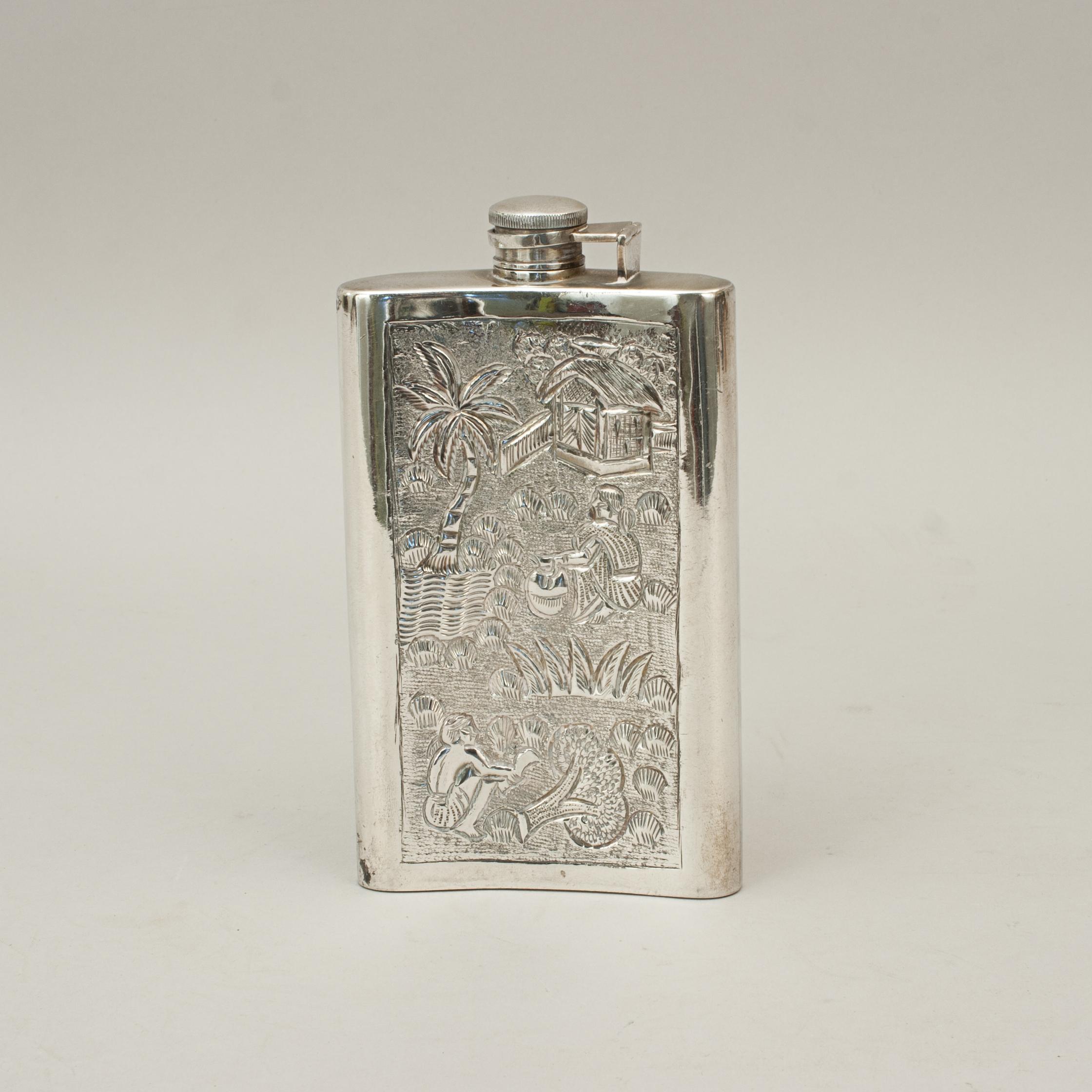 Gentleman's hip flask with eastern design.
A very nice large spirit hip flask with curved body and heavily embossed decoration. The flask with hinged screw lid. The decoration covering the flask is of elephant, bulls, thatched hut, a lady drawing