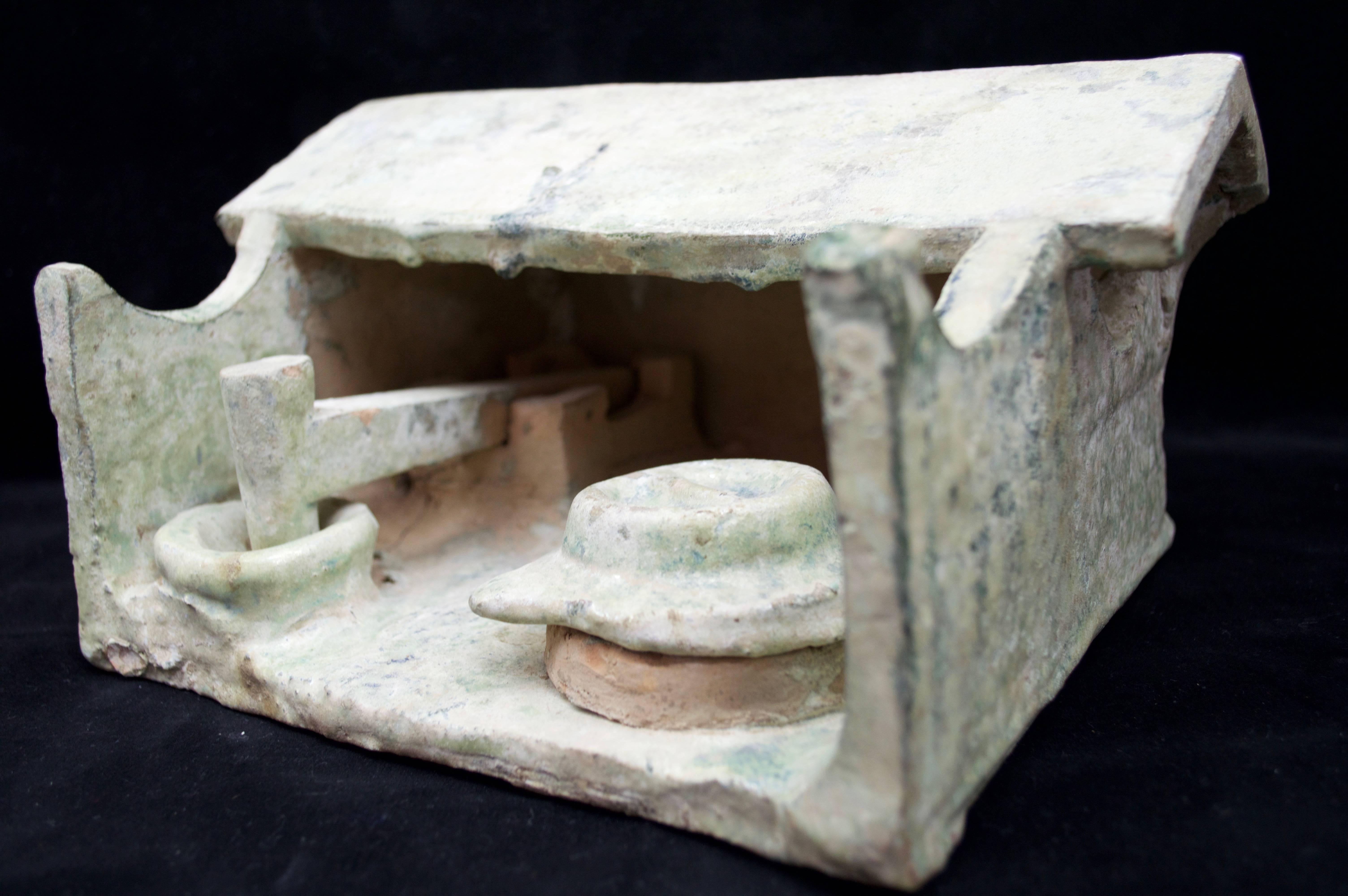 Slab pottery constructed barn workshop having a peaked roof – open walled form with a mechanical pounder and a large round covered storage container. Light blue-green mottled glazed surface with some iridescence patina to the glaze. 

Condition: