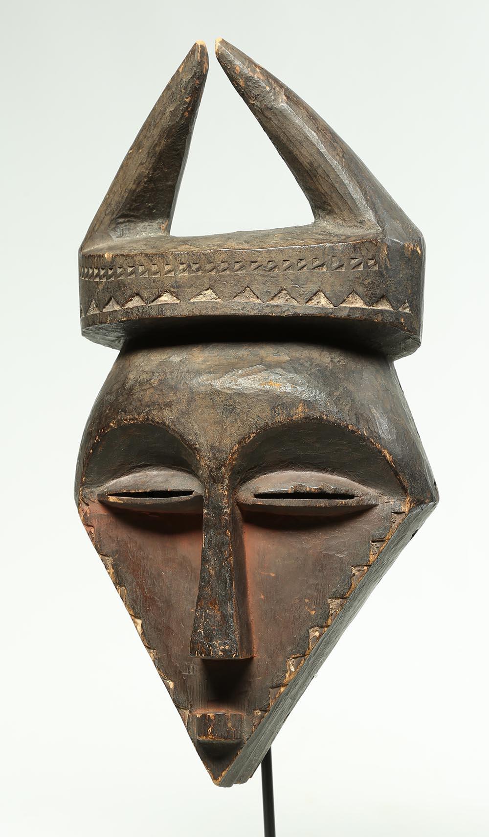 Large Eastern Pende mask with horns, Democratic Republic of Congo, Africa. Striking geometric, stylized face, two horns, traces of red pigments. On custom metal base, mask: 15 1/2 x 7 3/4 x 4 inches, total height with base 20 inches. De-accessioned