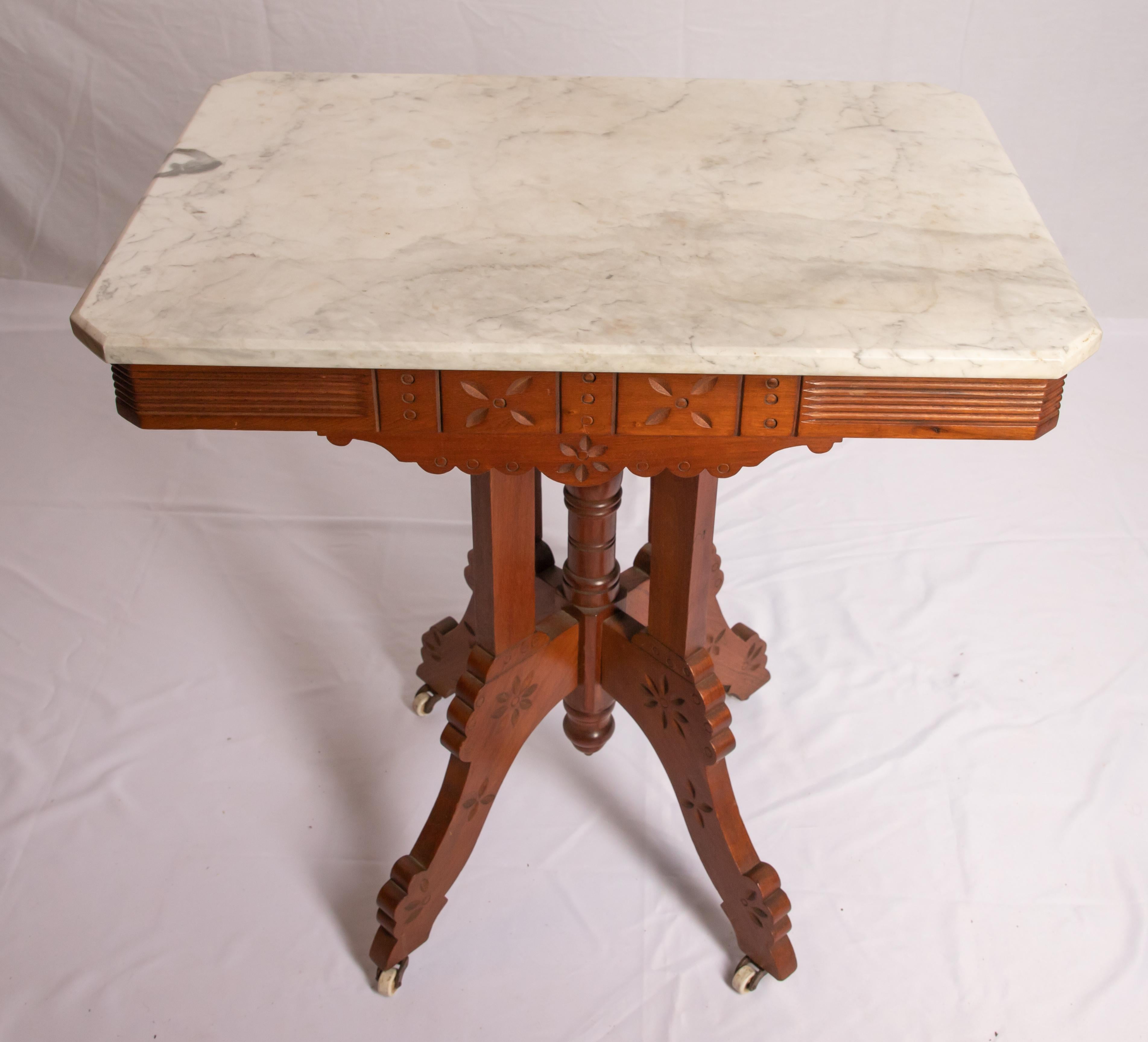 Offering this stunning Eastlake marble-top parlor table. Starting at the bottom on four legs that come to the center having some light floral carving. Rises from there on a center spindle that has four rectangle post around it. The skirt of the
