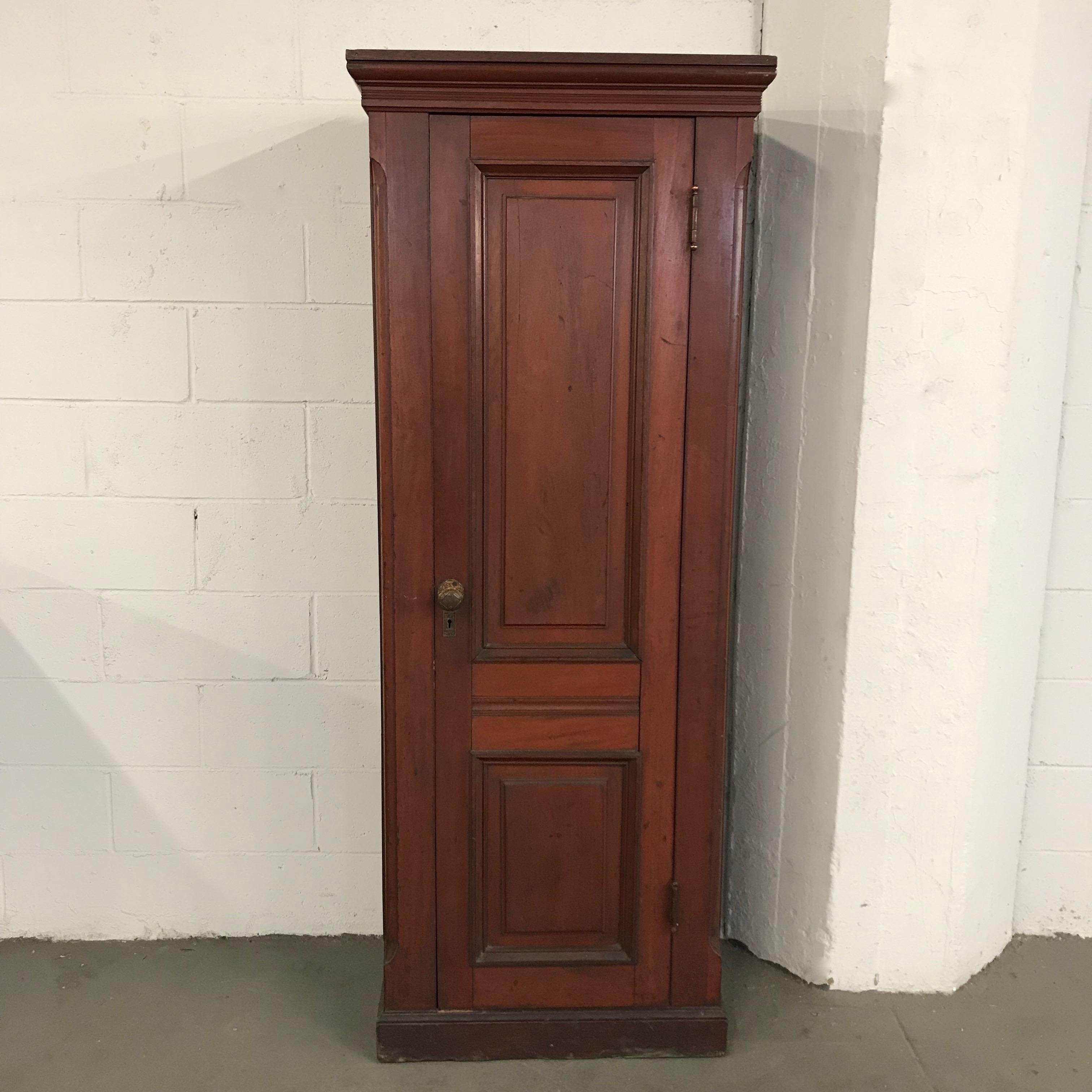 Eastlake, carved mahogany armoire cabinet with decorative, brass door knob has interior shelves for storage and can accept a rod on top for hanging clothes. The interior measures 23 inches wide and 13.5 inches deep.