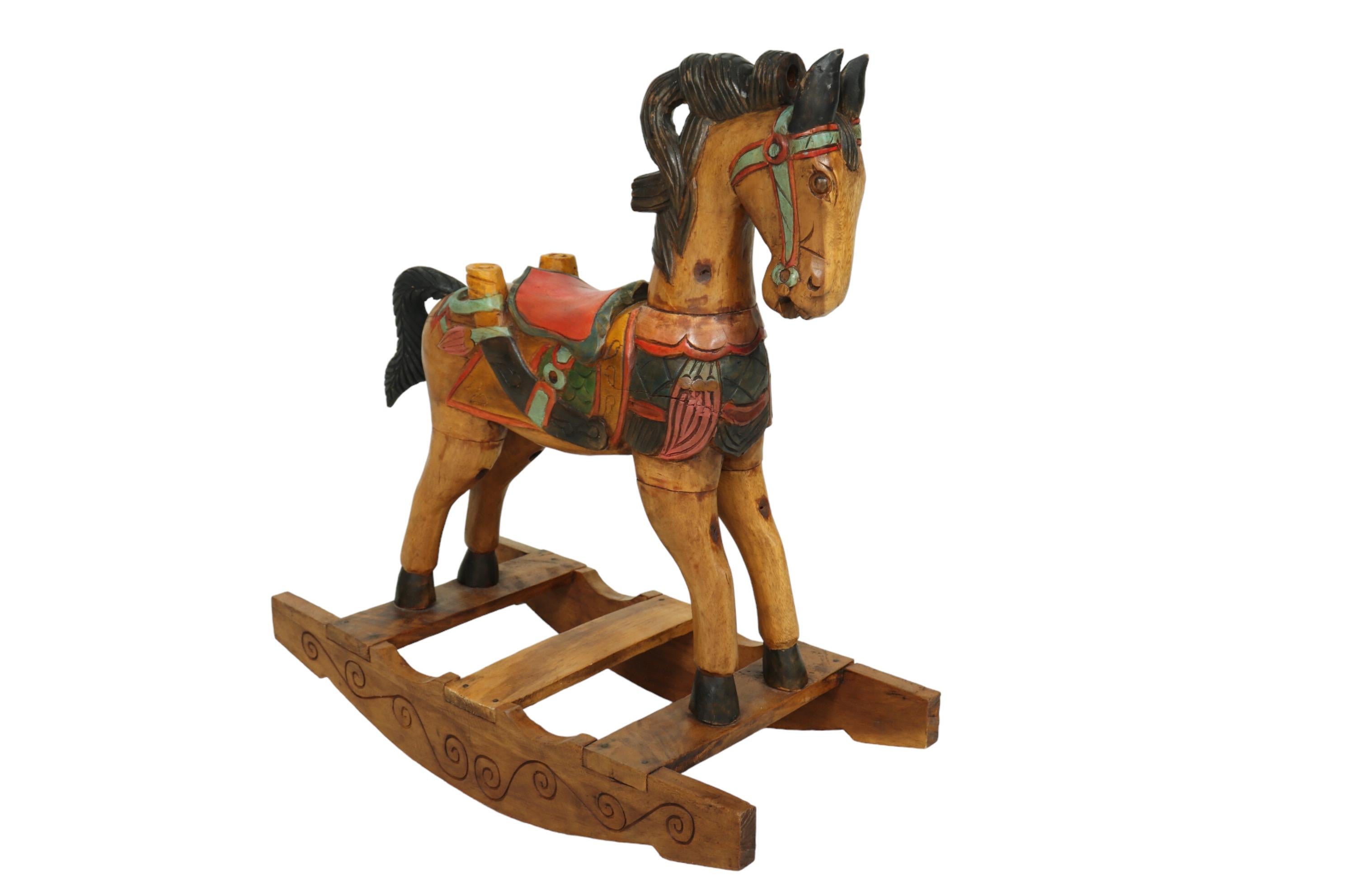 An Eastlake period carved rocking horse made of fruitwood. Beautifully carved throughout with attentive backward facing ears, round eyes and a curling mane. A colorful bridal and saddle are elaborately carved with scales, a wing motif and a sword