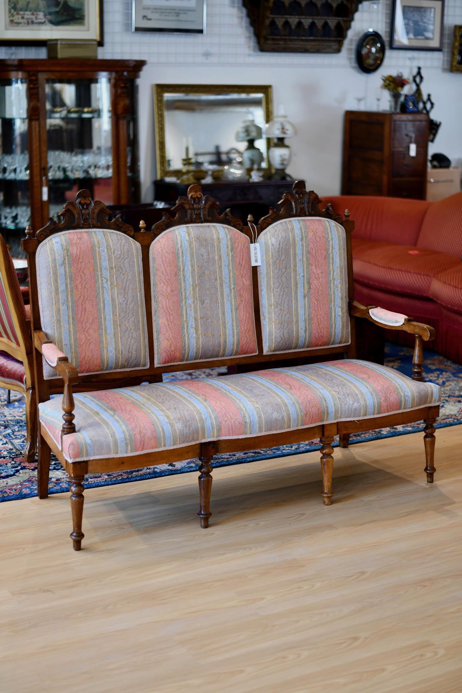 Eastlake Victorian canape settee in striped upholstery with carved frame. Upholstery likely newer than frame. In good vintage condition. Dimensions: 62