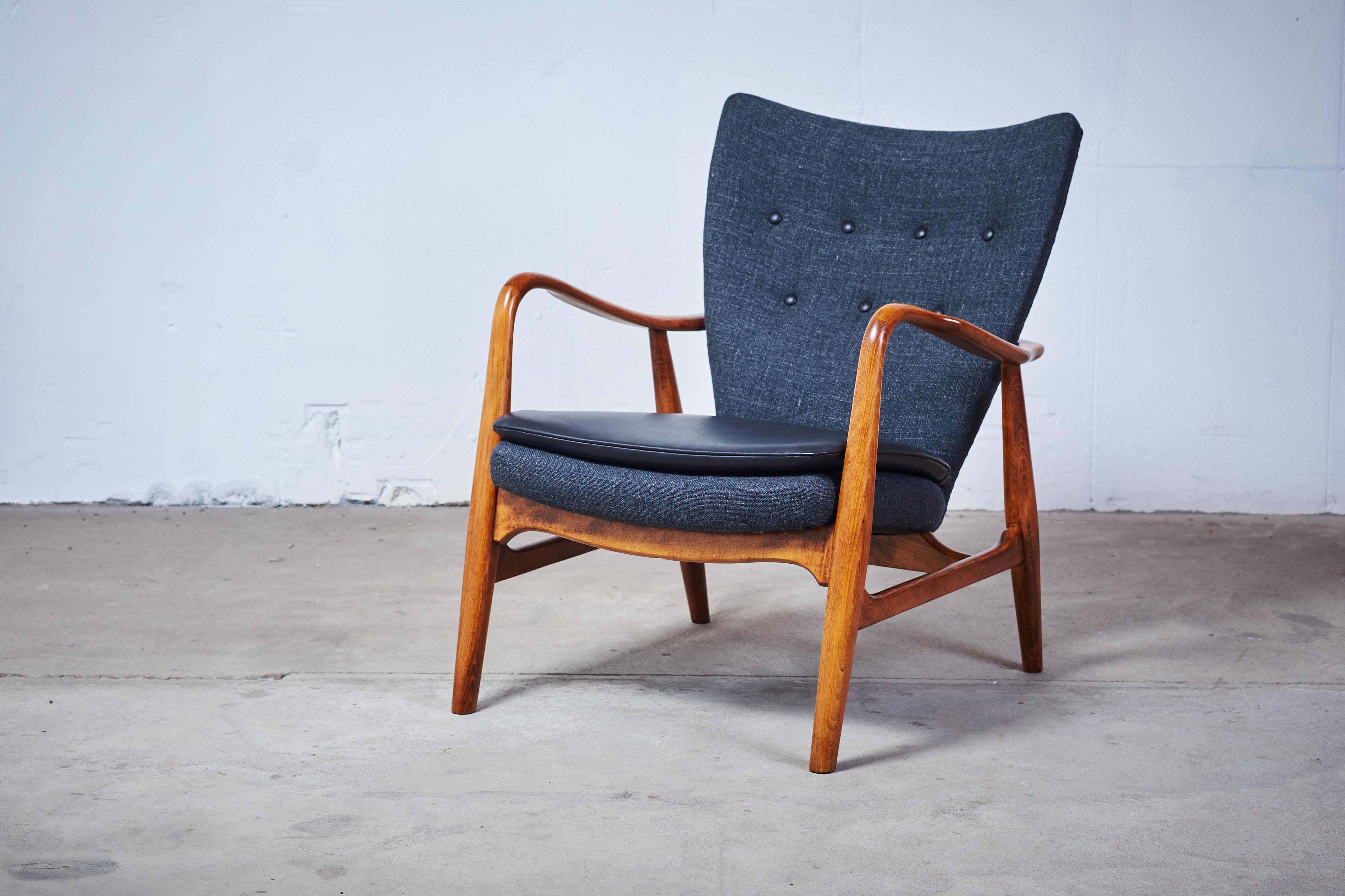 This stunning easy chair was manufactured in the 1950s by Madsen & Schubell in Denmark. It features a stained beech frame with a leather button fitted back with off grey fabric in great quality from Kvadrat from Denmark, seat cushion in black