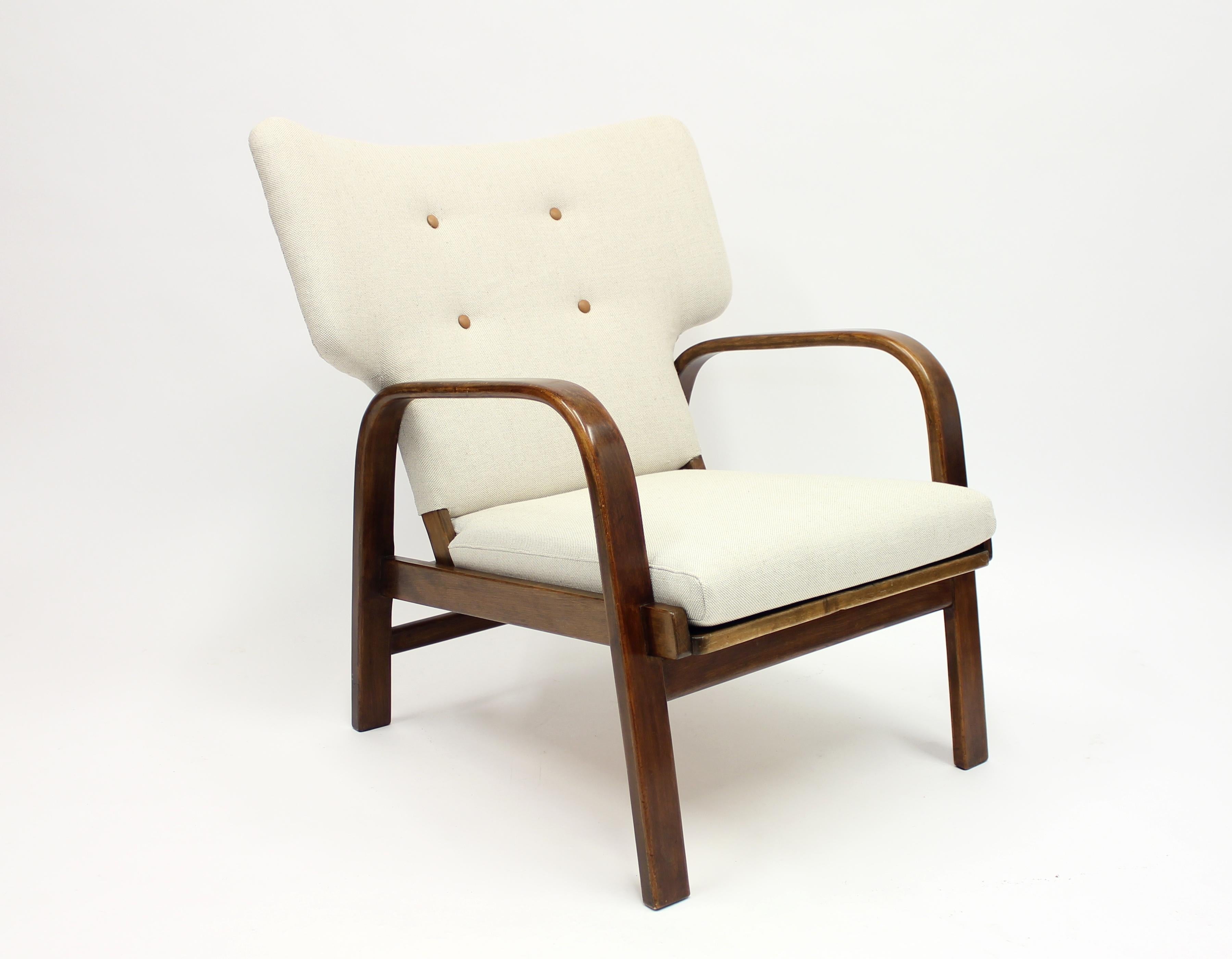 Danish easy chair designed by Magnus Stephensen with his almost trademark T-shaped form. Produced by legendary Danish manufacturer Fritz Hansen in the 1930s. Leg frame in stained beech with new off-white upholstery with brown leather buttons.