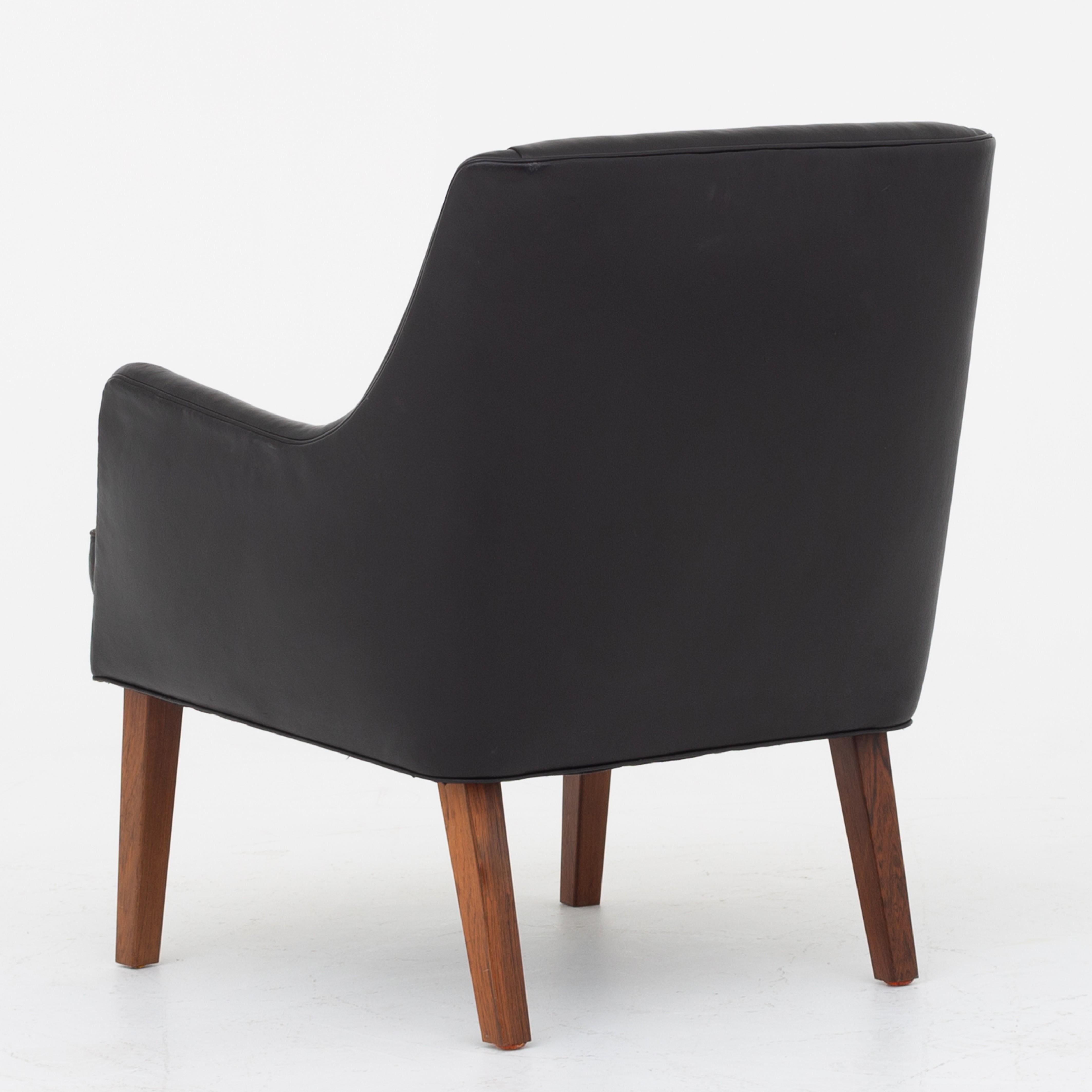 Easy chair in patinated black leather with legs of rosewood. Cabinetmaker Gustav Bertelsen.
