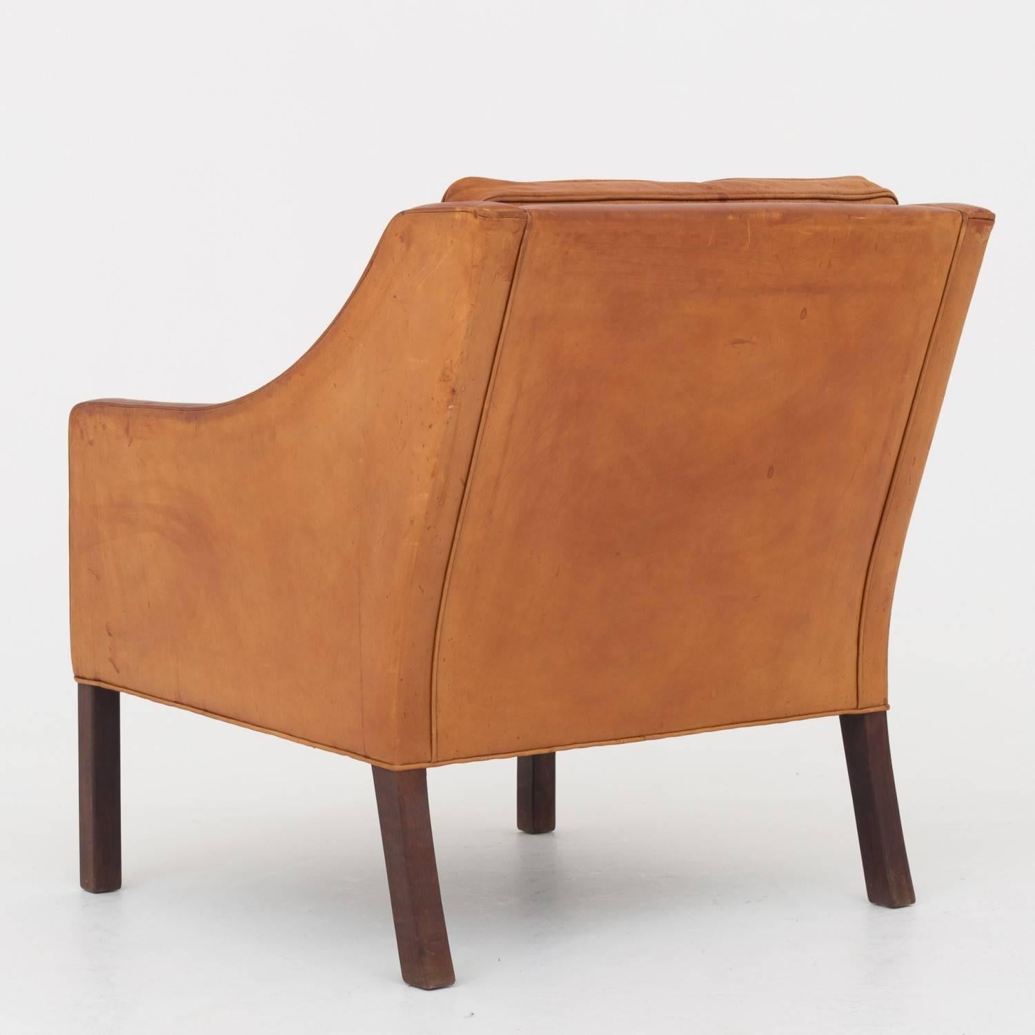 Easy chair in patinated natural leather. Legs in walnut. Matching two-seat is available. Made at Fredericia Furniture.