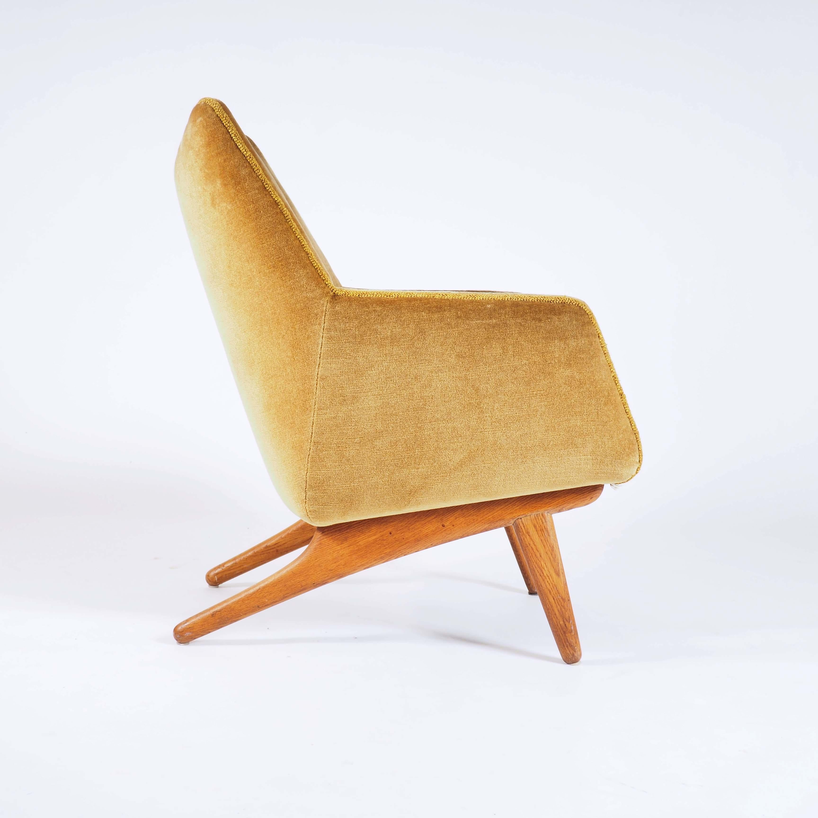 This rare easy chair was designed by the Danish architect Illum Wikkelsø. The silhouette of the legs are very typical for his design. It has original upholstering in velvet and the legs are in solid oak.