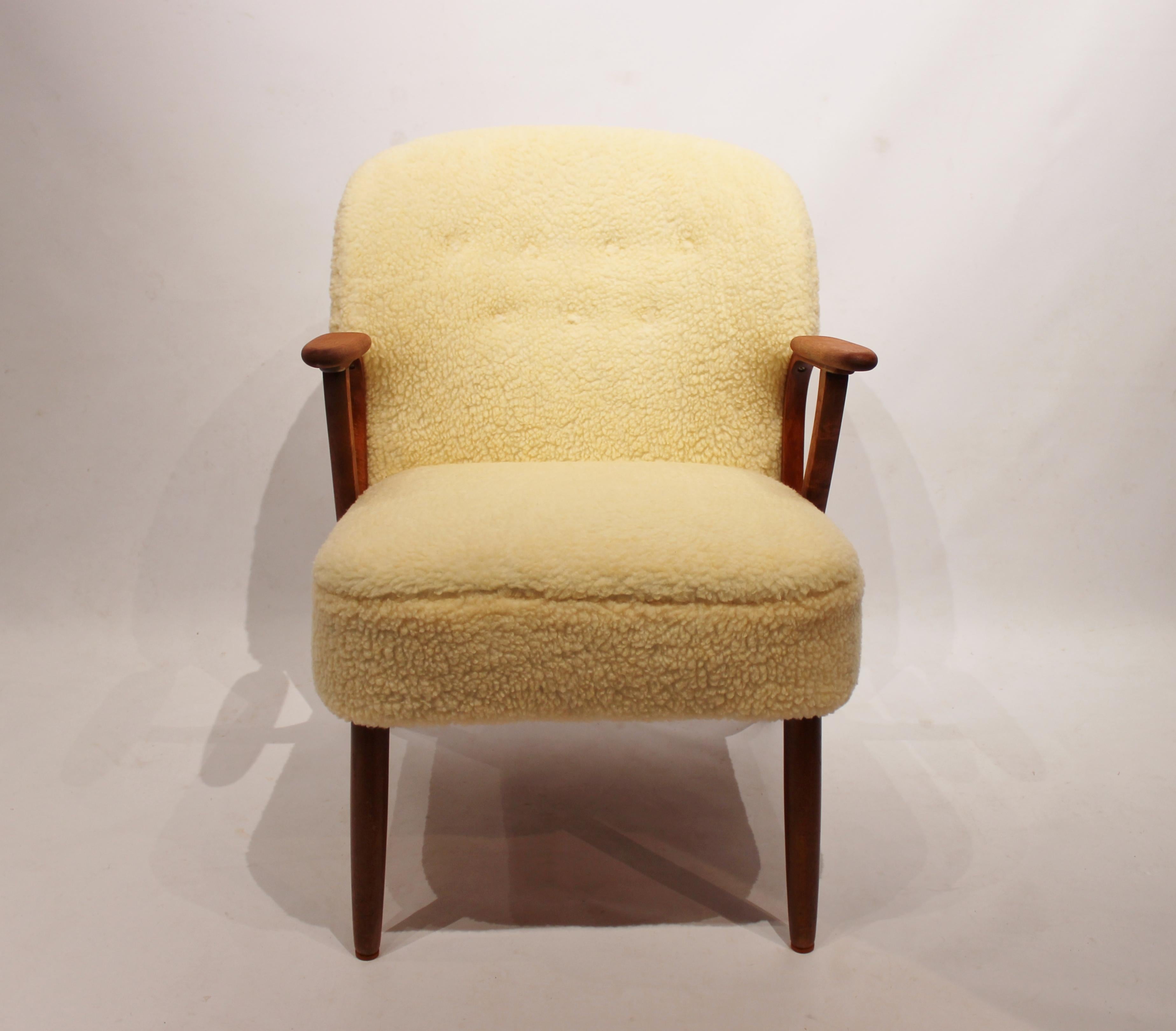 Easy chair upholstered in sheep wool and with arms of dark wood of Danish design from the 1960s. The chair is in great vintage condition.