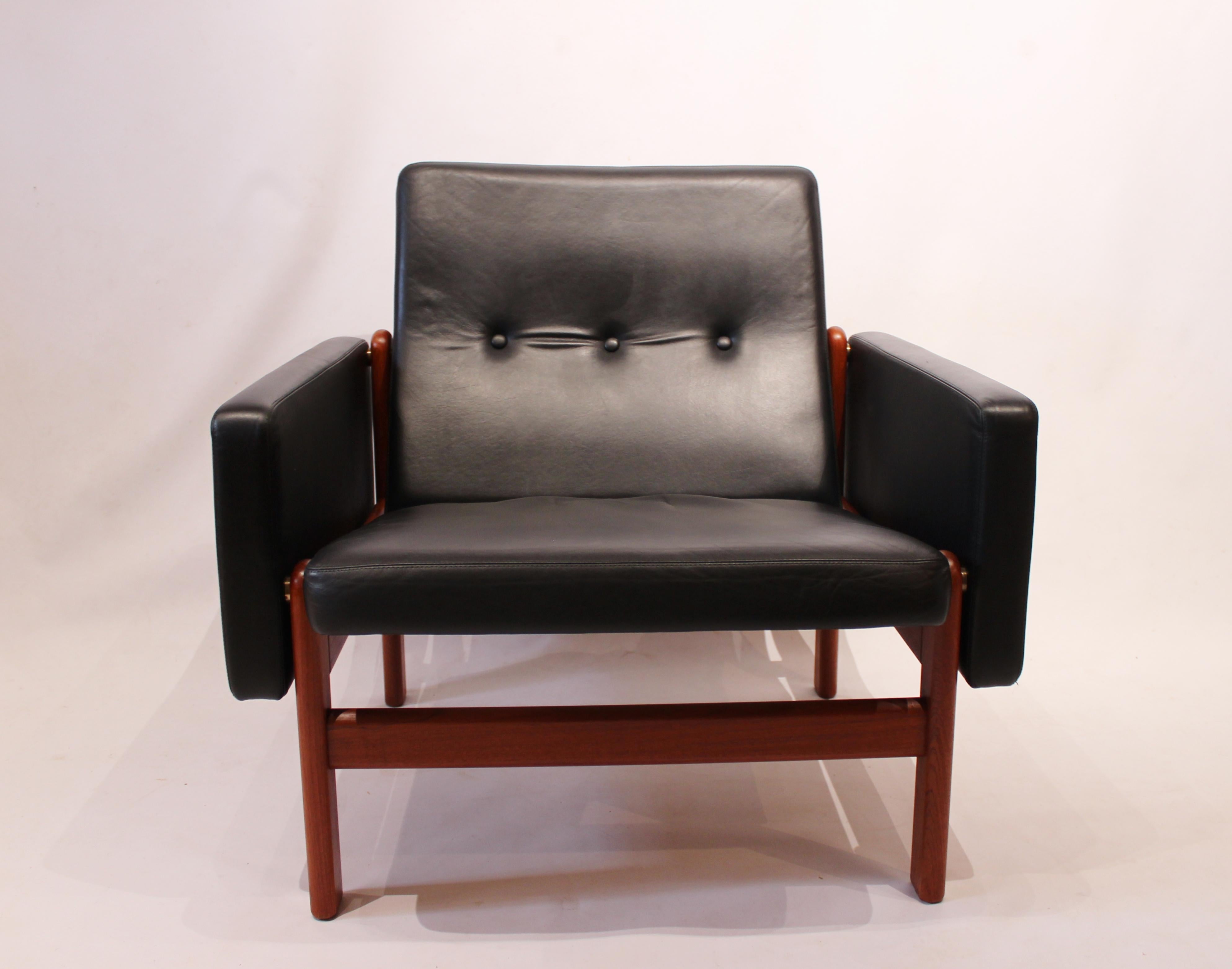 Sessel, Modell 65 23, mit Hocker, Modell 64 23, gepolstert mit schwarzem klassischem Leder und Gestell aus Teakholz. Der Stuhl und der Hocker wurden von Jørgen Bækmark entworfen und von FDB in den 1960er Jahren hergestellt und befinden sich in einem