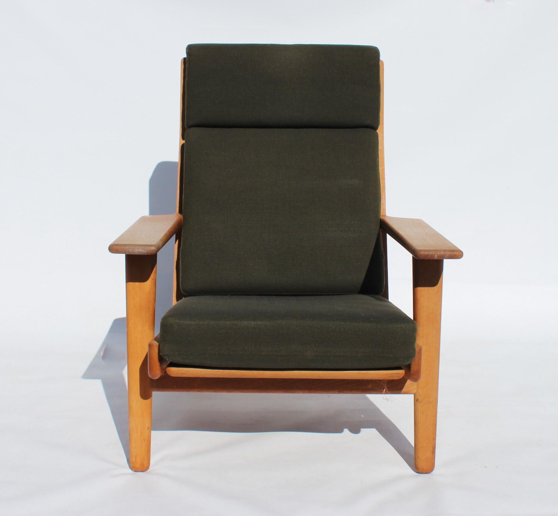 Easy chair with tall back, model GE290A, designed by Hans J. Wegner and manufactured by GETAMA in the 1960s. The chair is of soap treated oak and upholstered with dark green Hallingdal wool.