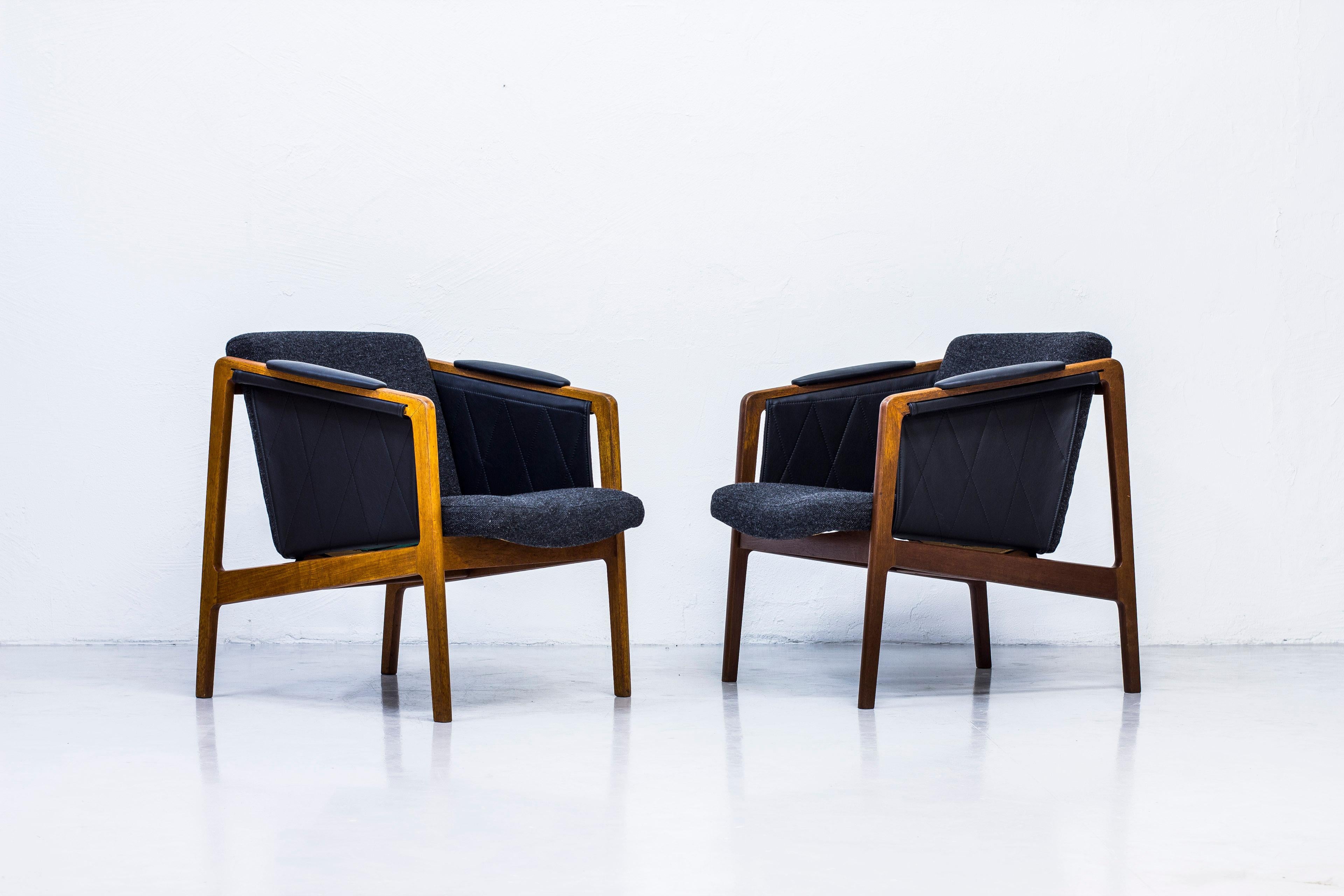 Rare easy chairs designed by Bjørn Engø. Produced in Norway by Møre Lenestolfabrikk. designed circa 1958. Made from solid teak with sides and armrests in new black leather. Seats reupholstered in Hallingdal 65 from Kvadrat. Good condition with age