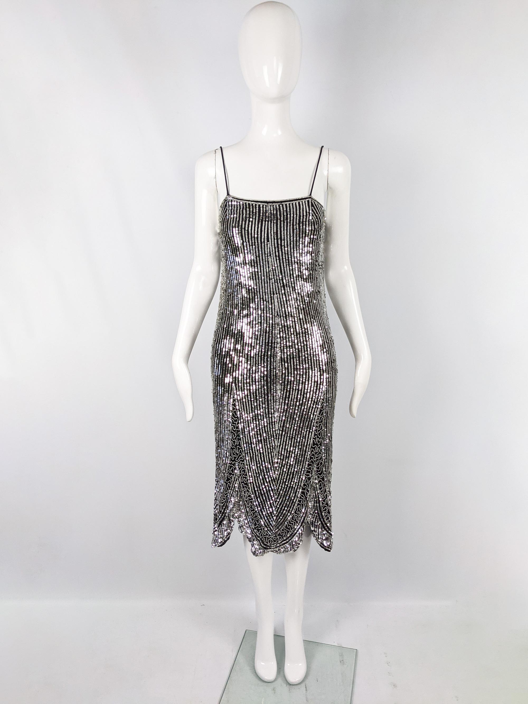 A chic vintage womens party dress from the 80s in a 1920s flapper style by luxury British fashion house, Eavis & Brown, known for their opulent, heavily embellished evening wear. This is in a black pure silk covered in silver sequins and glass beads
