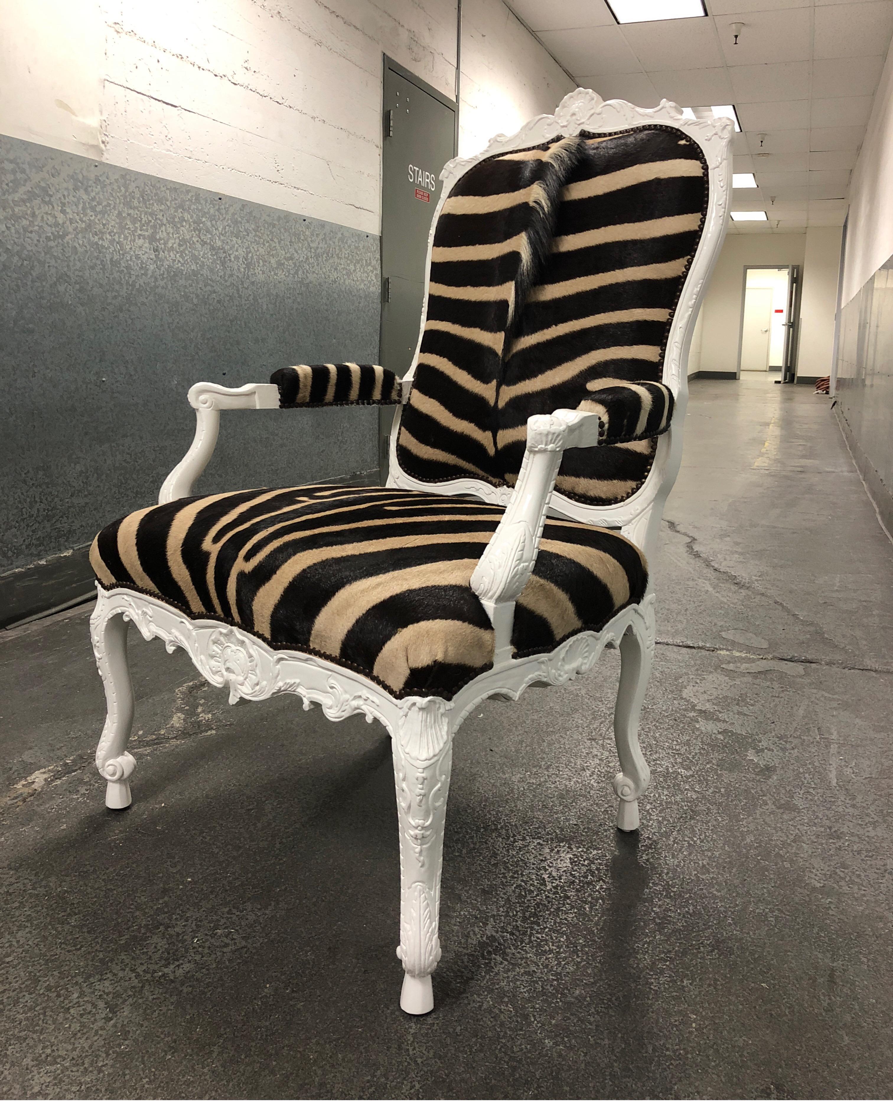 A Jesi armchair by Ebanista. A hand-carved armchair with a white lacquer finish. Antiqued bronze finish nail head trim along seat and back. Upholstered in a South African hide. Measures: Arm height: 27.5 inches, seat height: 20 inches.
     
