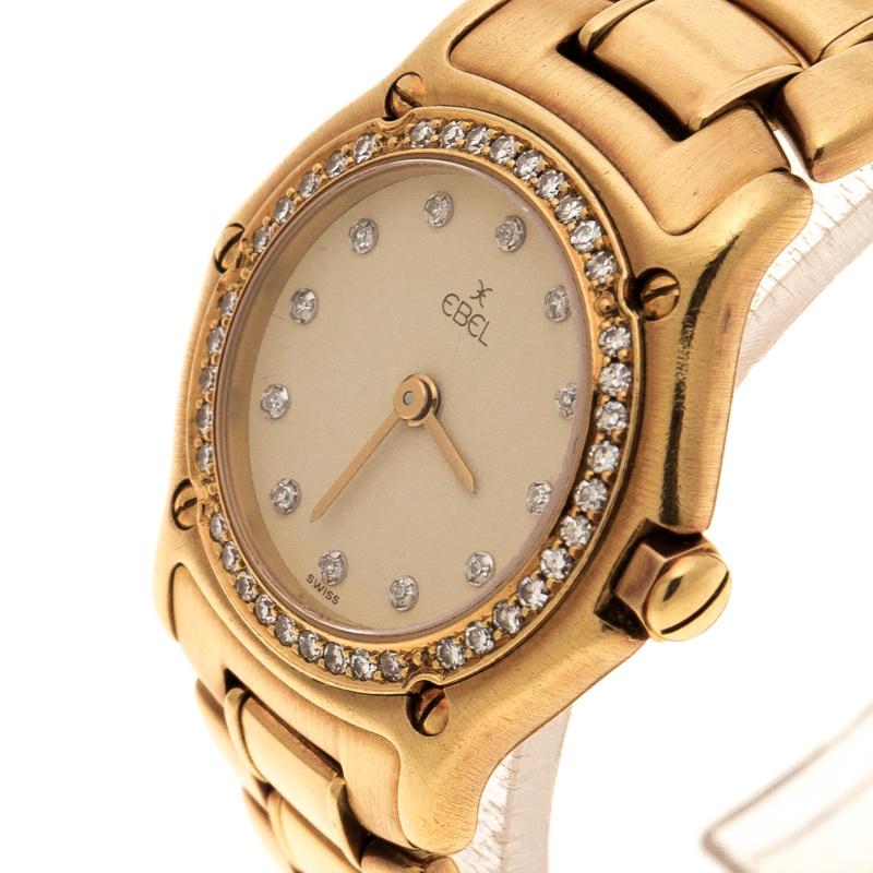 Powered by quartz movement, this Ebel wristwatch features an 18k yellow gold body and a rounded dial. The cream dial of this watch features a diamond-studded markers and gold-tone hands. It comes with a diamond-embedded bezel and surrounded by screw