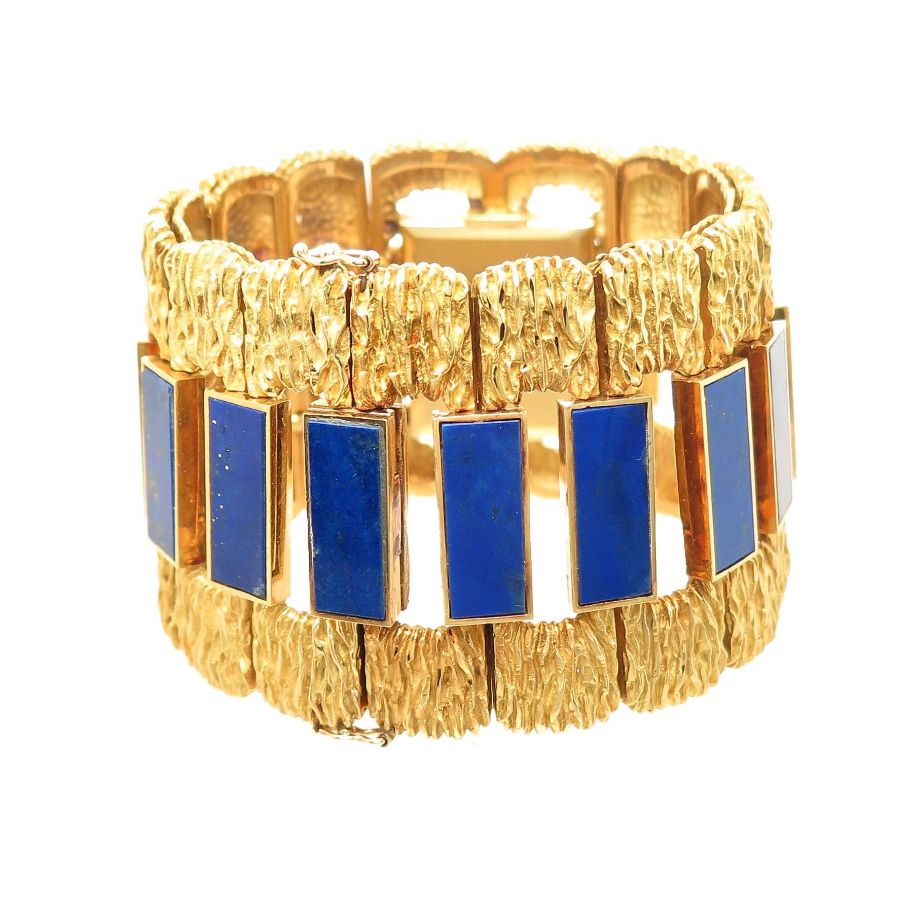 Circa 1970 Ebel 18K Yellow Gold Wrist watch, measuring 6 3/4 inches in length with a slight wrist fitting curve and 1 5/8 inches wide. Set with sections of fine Blue Lapis Lazuli. 17 Jewel Mechanical, Manual wind movement, Lapis Dial. A large and