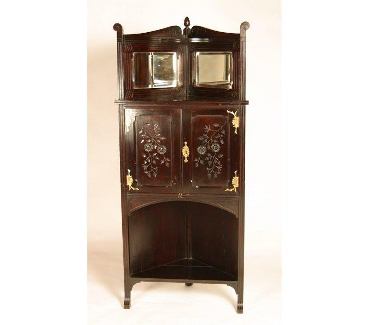 An Aesthetic Movement Mahogany Corner Cabinet with floral decoration to the upper shelf area, and to the doors incised decoration of circular flower heads and leaves radiating down with applied stylised hinges and escutcheon, a large lower display