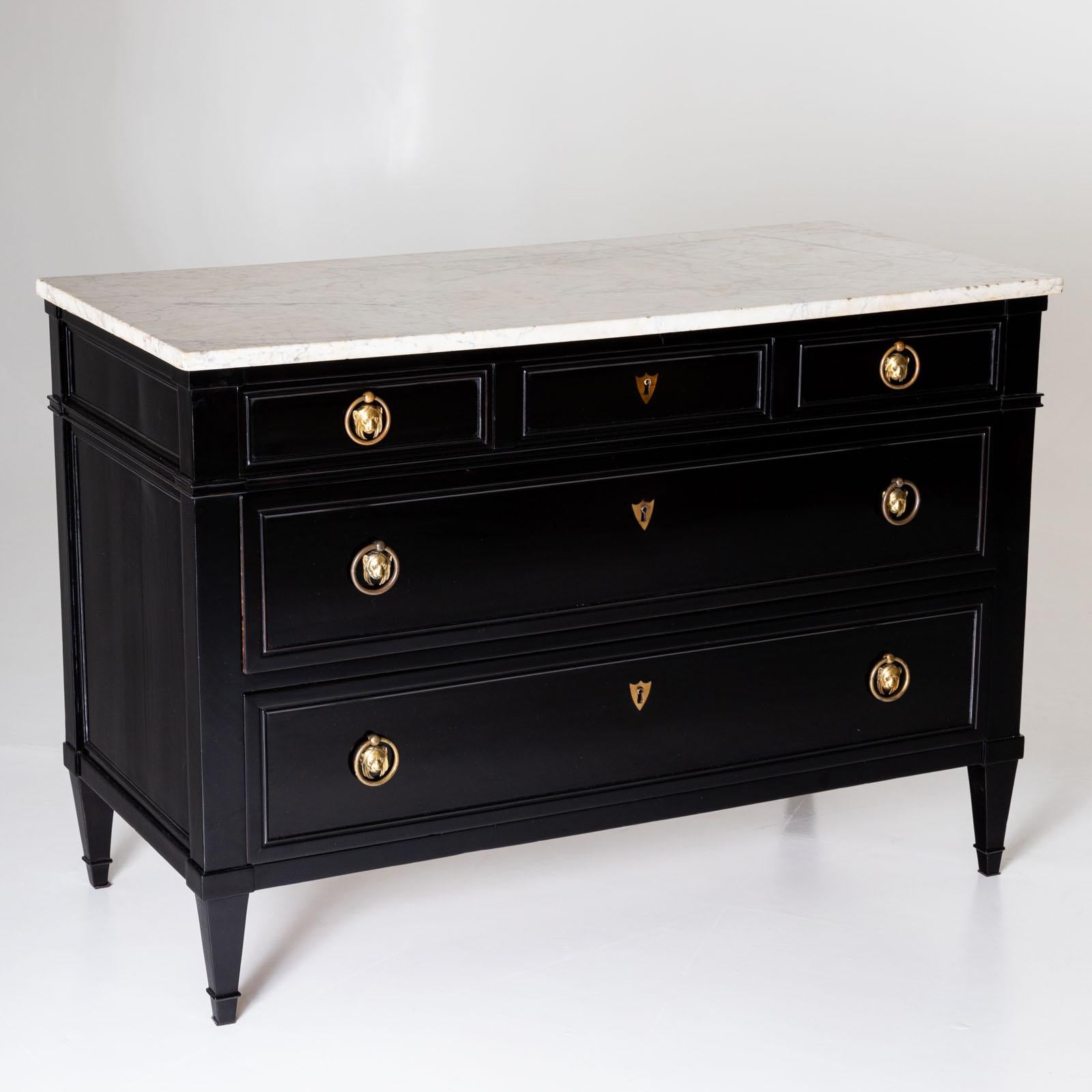 Large French chest of drawers with ebonised body and white marble top. The chest of drawers is fitted with five drawers and decorated with bronze fittings in the form of lion mascarons. Restored and hand-polished condition. 