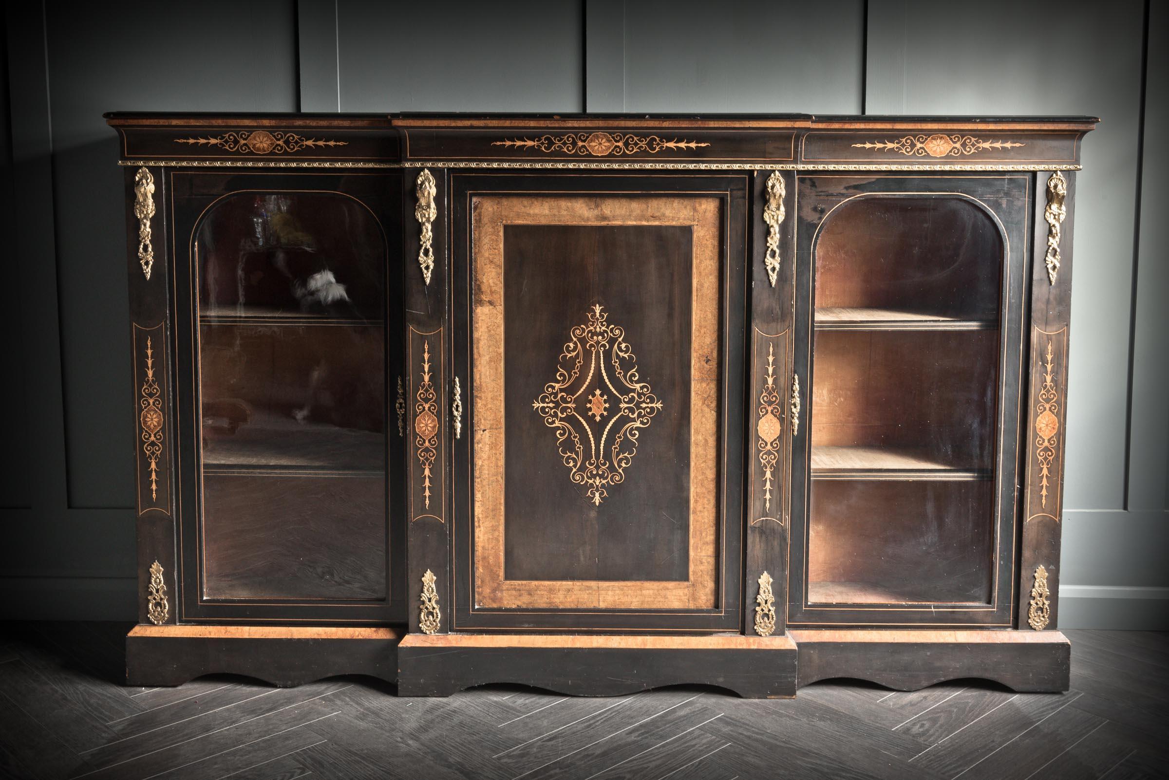 This stunning, ebonised bronze decorated three door Credenza is the work of a master craftsman during the mid-Victorian period.
The central door is decorated with a gold design. It is flanked by two glazed doors with built in shelves. The doors