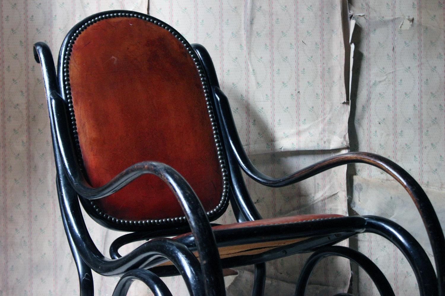 The Classic Vienna Secession style bentwood rocking chair having an ebonised scrolling frame to burgundy leather upholstery with brass hobnails, the finish to each surface now beautifully worn and surviving from the early twentieth century.

The