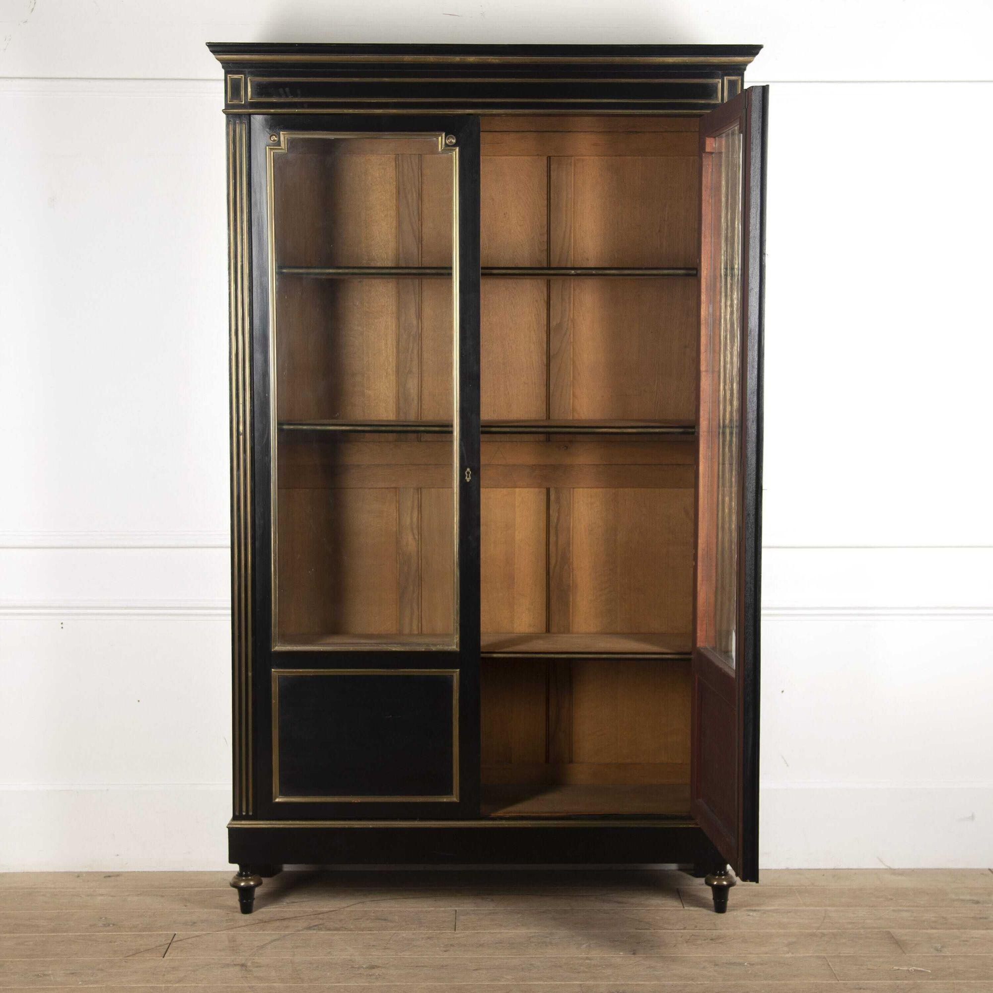 Fantastic French two-door ebonised bookcase with brass detail.
This bookcase dates from the early 20th Century and has two glazed and panel doors and adjustable internal shelves. This bookcase can be dissembled with ease for storage or ease of