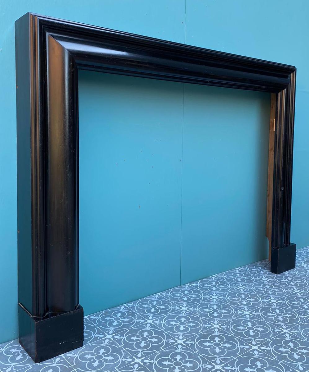 A reclaimed ebonized wood Bolection style fire mantel. This striking bolection fireplace showcases rich ebonized wood with a deep black glossy finish, instilling any space with style and finesse. With a desirable size, this fire surround is suitable