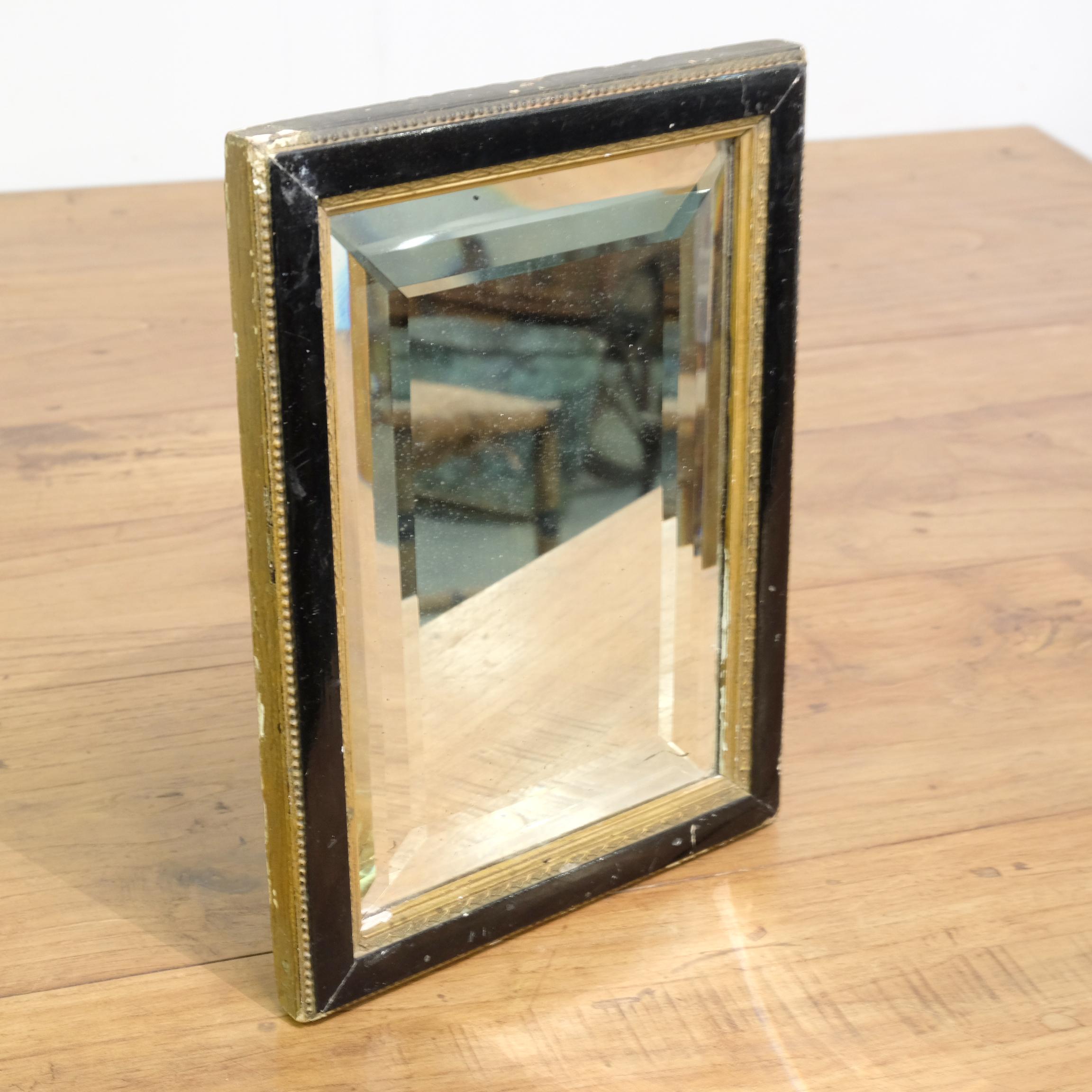 An utterly charming little French mirror with the unusual and interesting addition of a double bevel to the gently distressed original glass. Ebonized and gilt frame in original condition with age related wear and losses, late 19th century. Such a