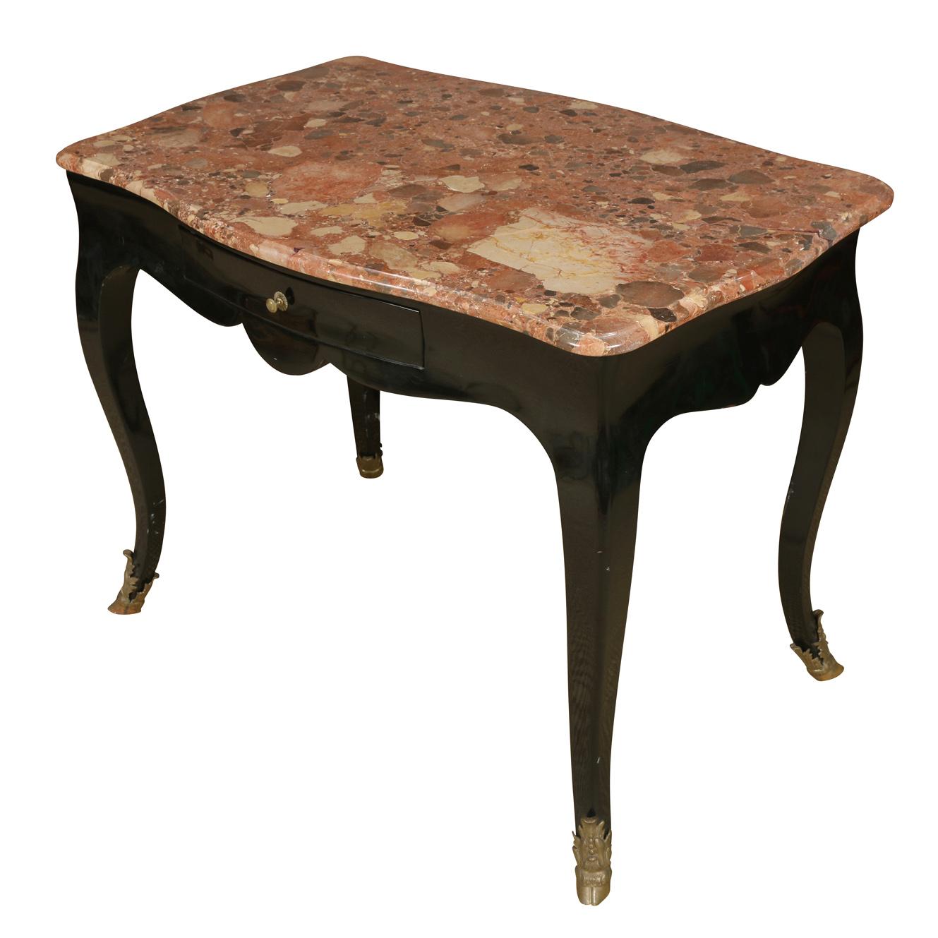 Ebonized antique French writing desk with coral marble top, a single drawer, and cabriole legs ending in brass hoof caps.